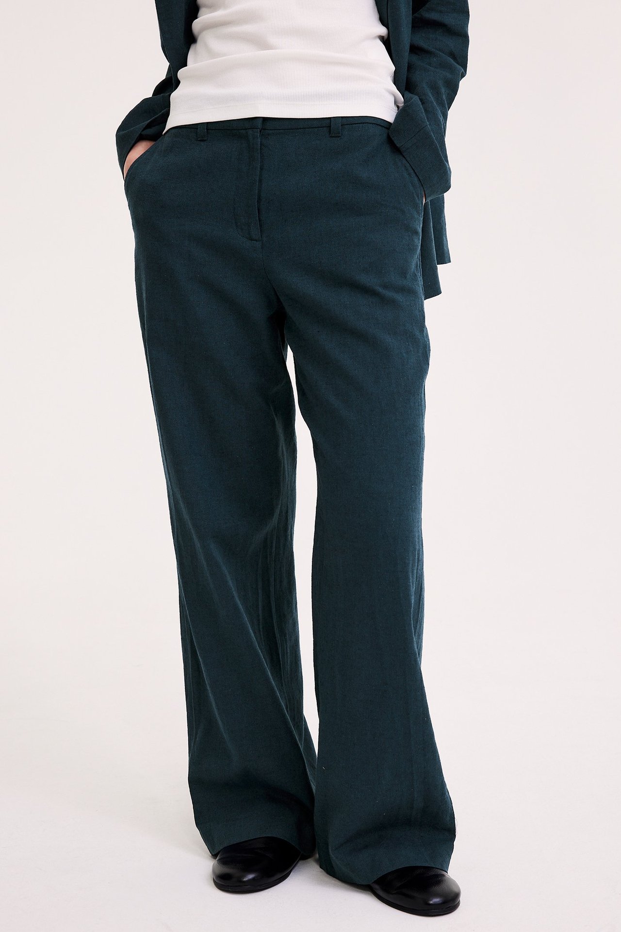 Edestäpäin: Nainen tummansinisissä meleeratuissa pellavasekoitehousuissa, valkoinen toppi ja bleiseri.