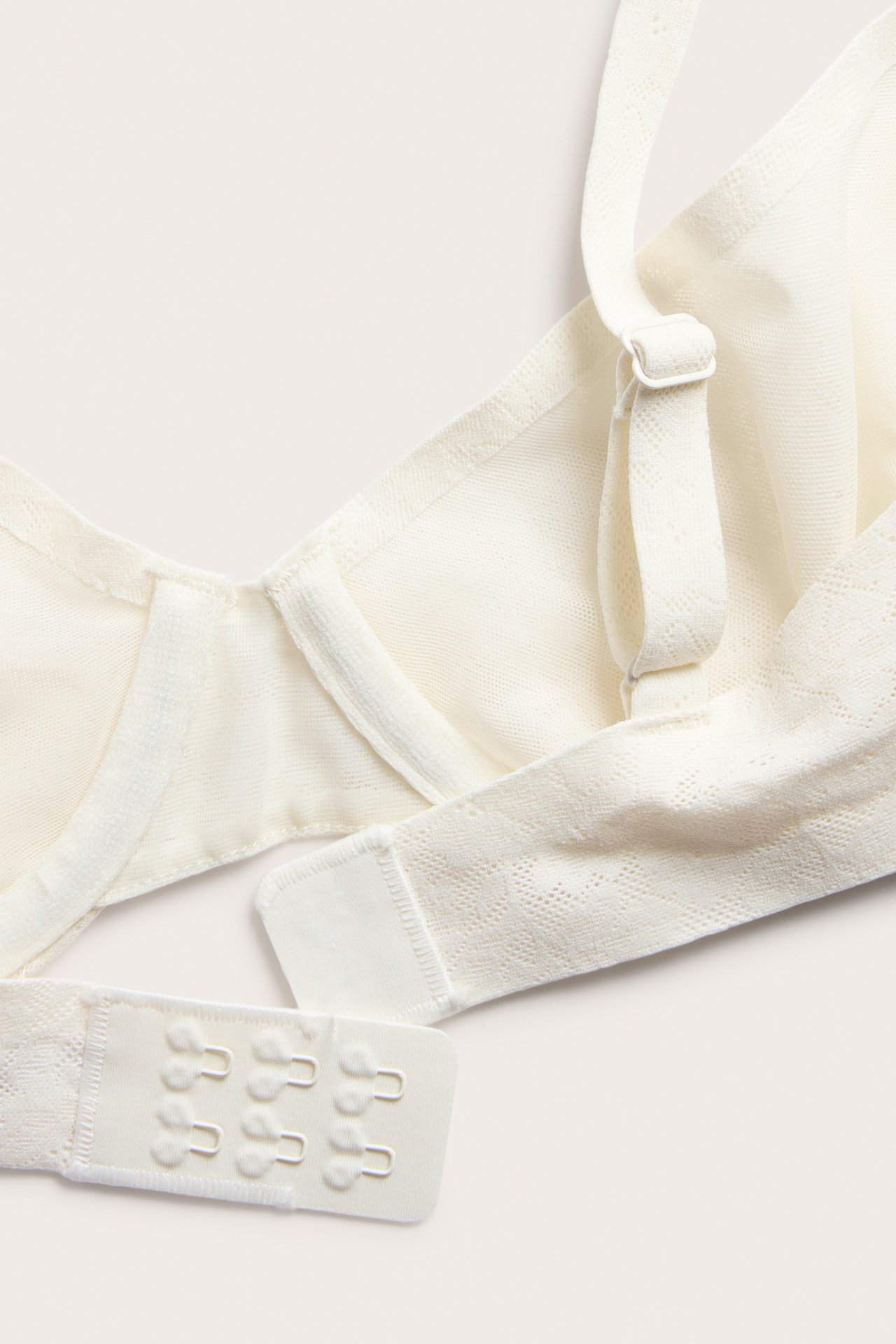 Zbliżenie biustonosza z fiszbinami ecru, elastyczna koronka, regulowane ramiączko i haftki.