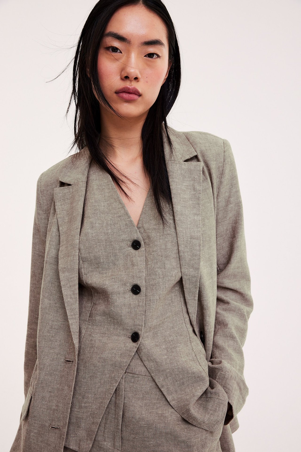 Frontvy av kvinna i melerad brun linneblandningskavaj över en matchande väst.