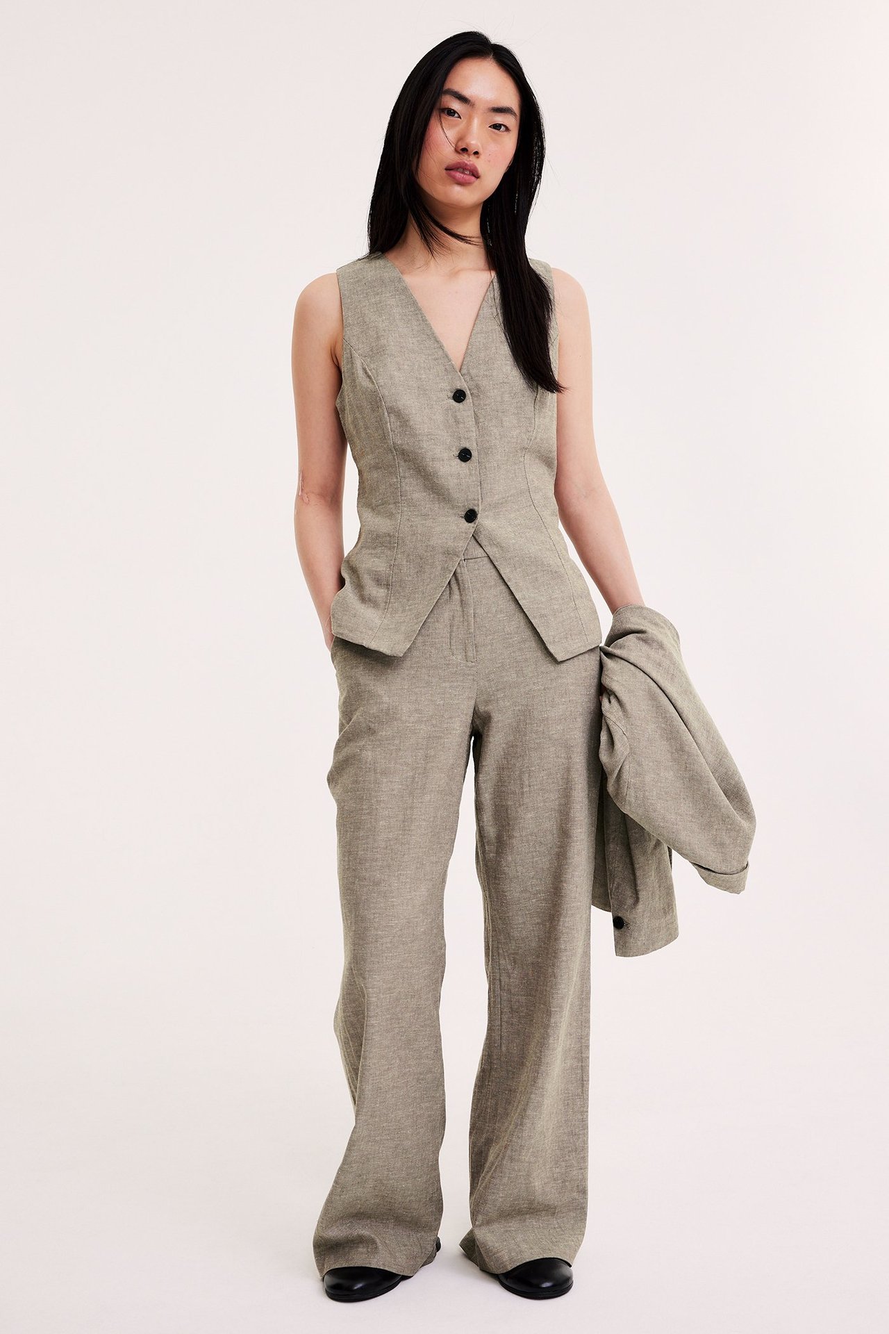 Edestä: Nainen yllään kirjavan ruskea pellavasekoite liivi, yhteensopivat leveät housut, pitäen takkia.