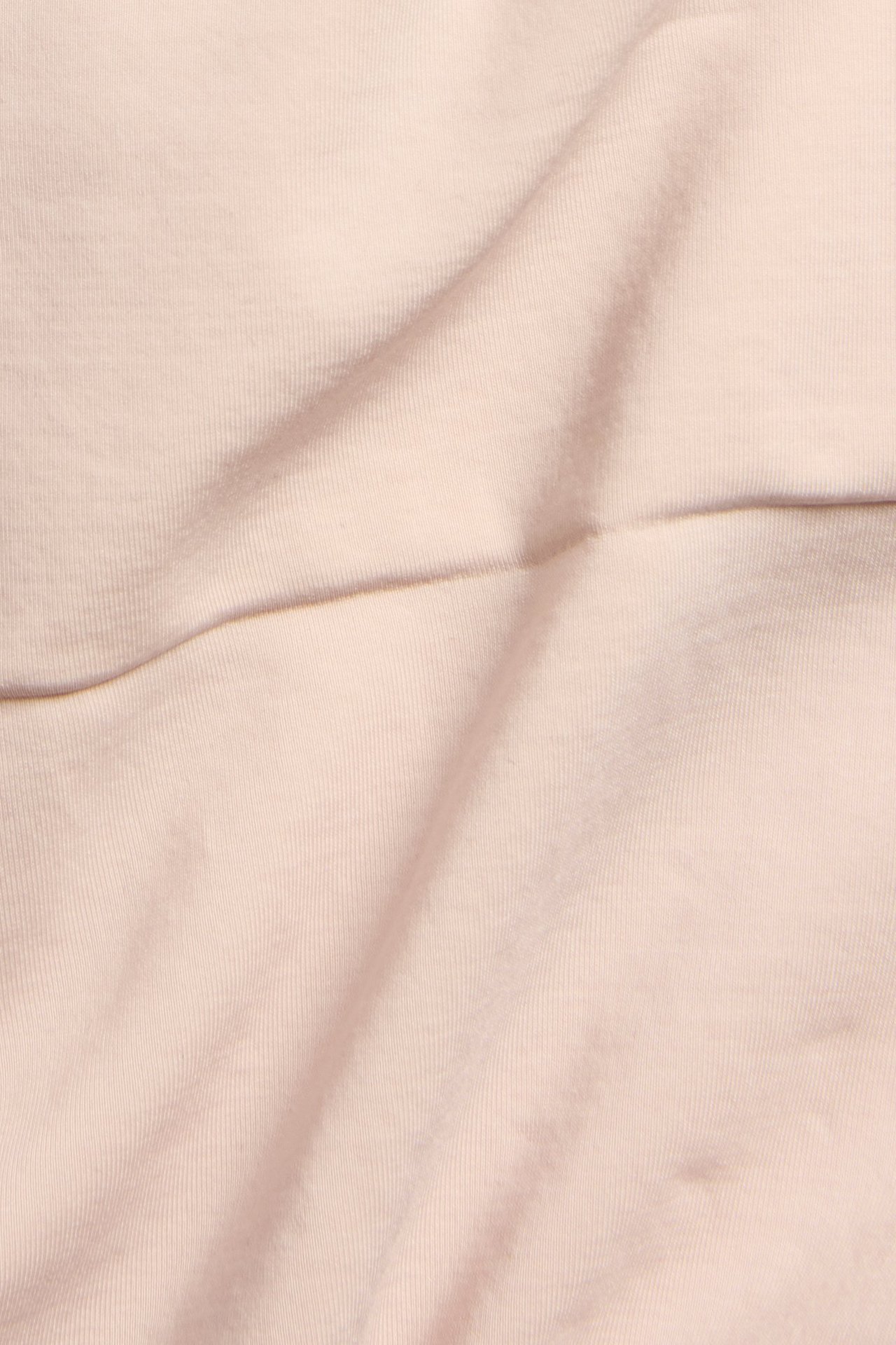 Nærbilde av lyserosa sømløs shapingshorts-stoff, viser en glatt, ensfarget tekstur.