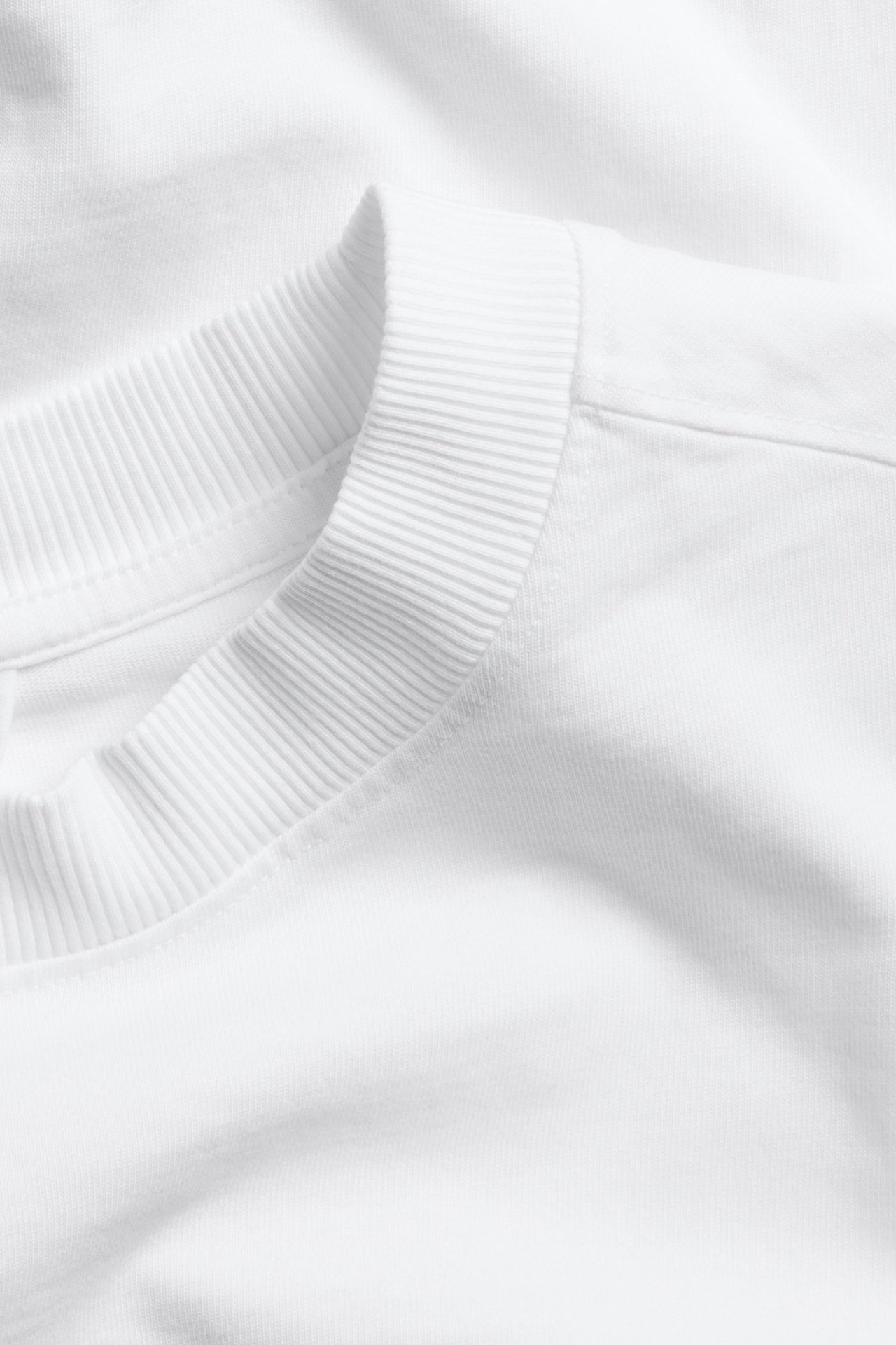 Zbliżenie na biały bawełniany T-shirt z prążkowanym okrągłym dekoltem.