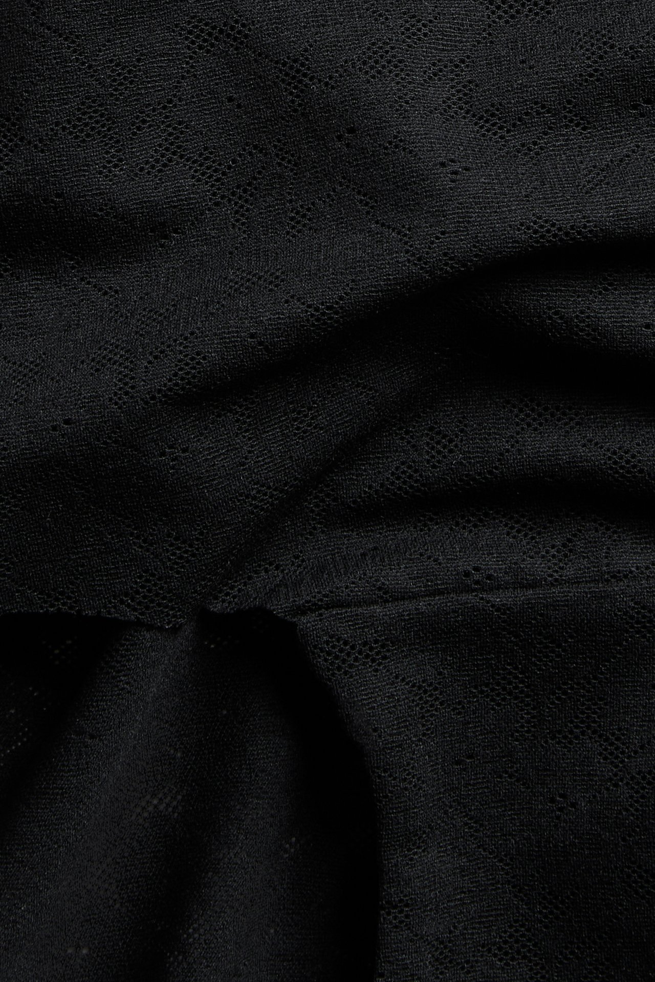 Närbild på svarta stretchiga spetshipstertrosor med ett delikat mönster.