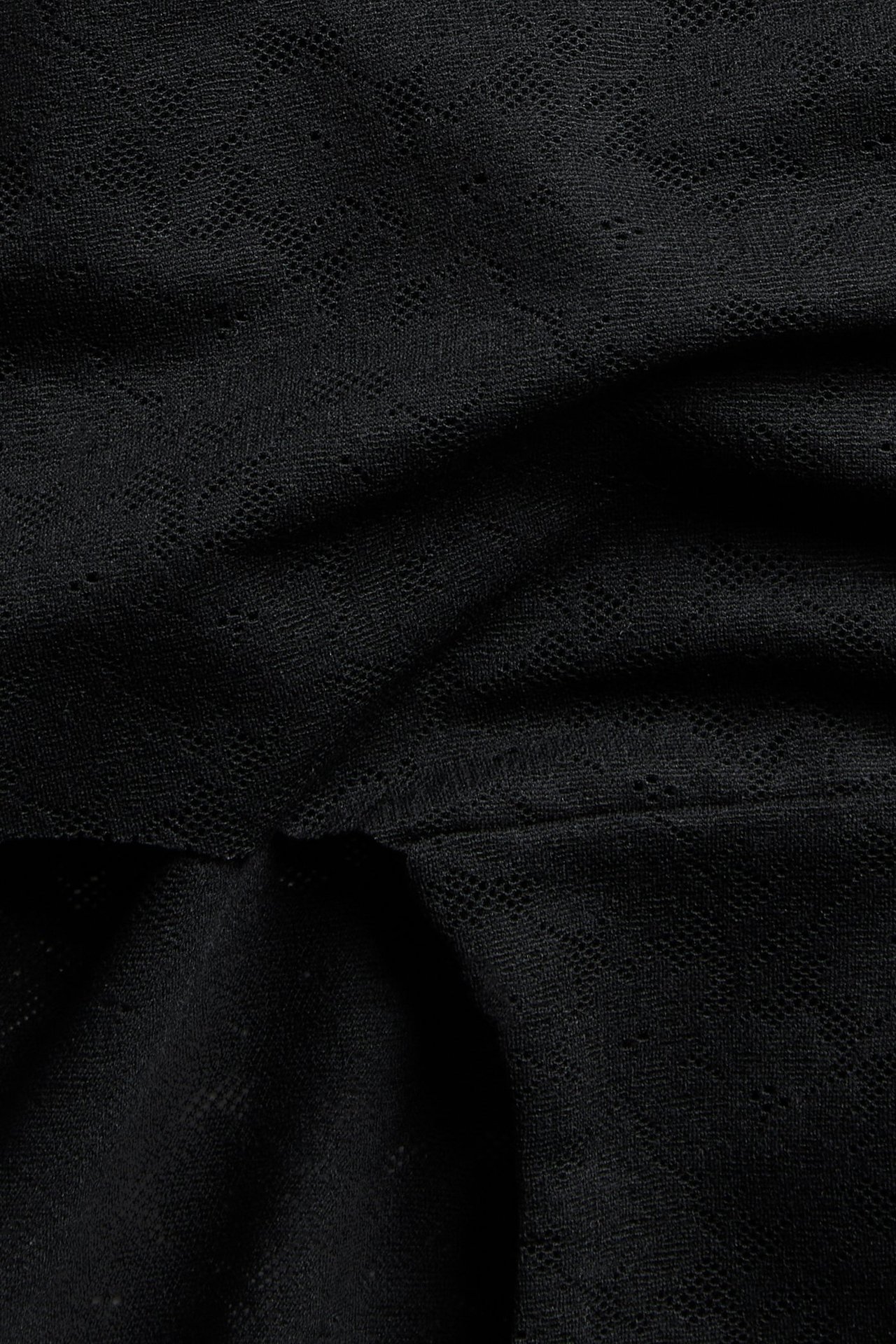 Närbild på svarta stretchiga spetshipstertrosor med ett delikat mönster.