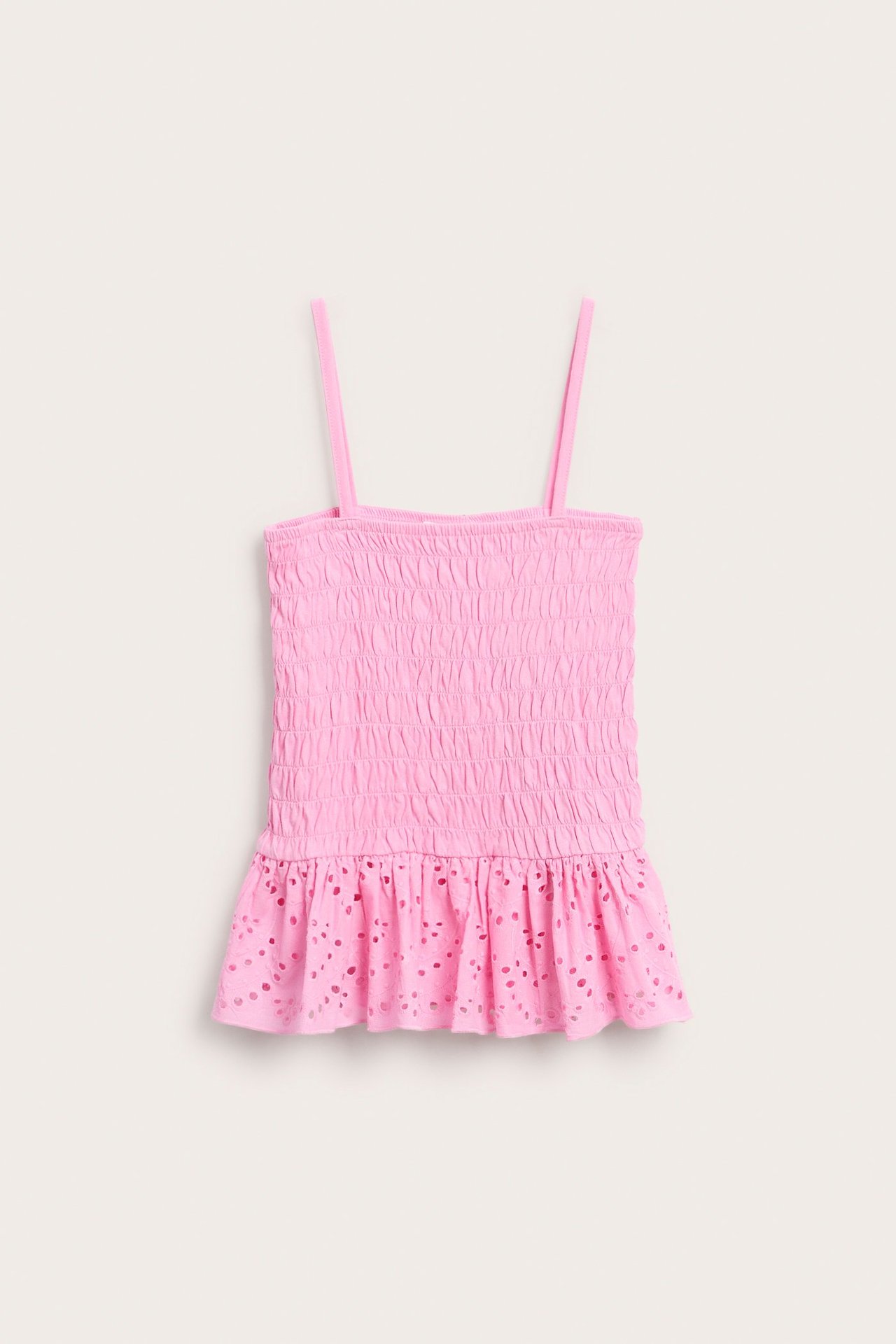 Widok z przodu: różowy, marszczony top na ramiączkach dla dziecka z falbanką i ażurowym brzegiem.