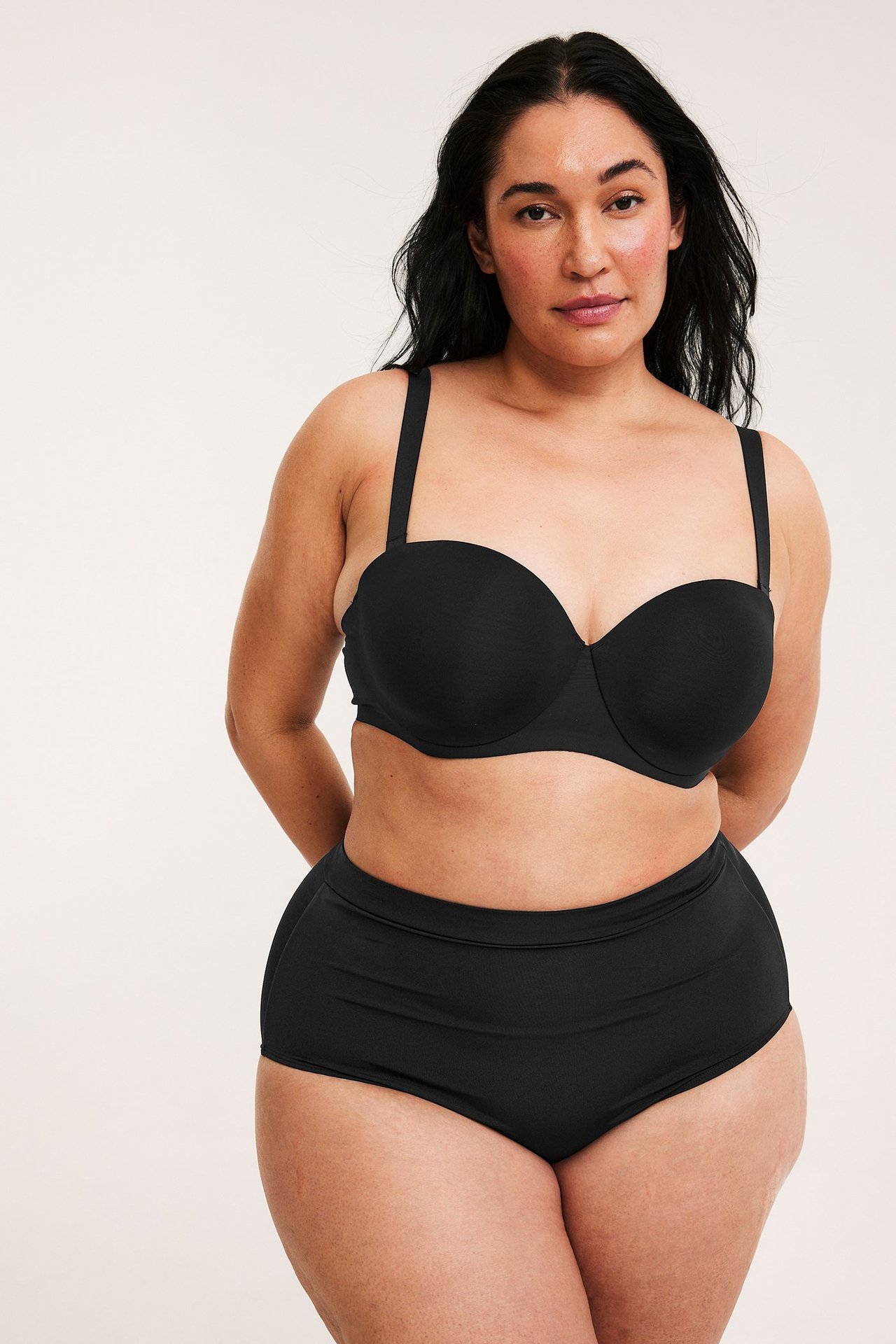 Widok z przodu: kobieta w czarnym biustonoszu balconette z ramiączkami i pasujących czarnych majtkach z wysokim stanem.