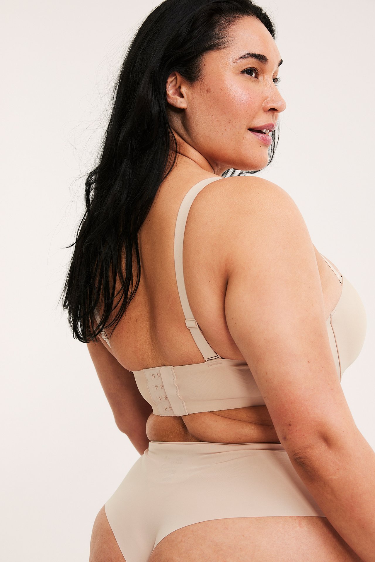 Rygg-sidebilde av en kvinne i lys rosa mikro balconette-BH med hektefeste og matchende truse.