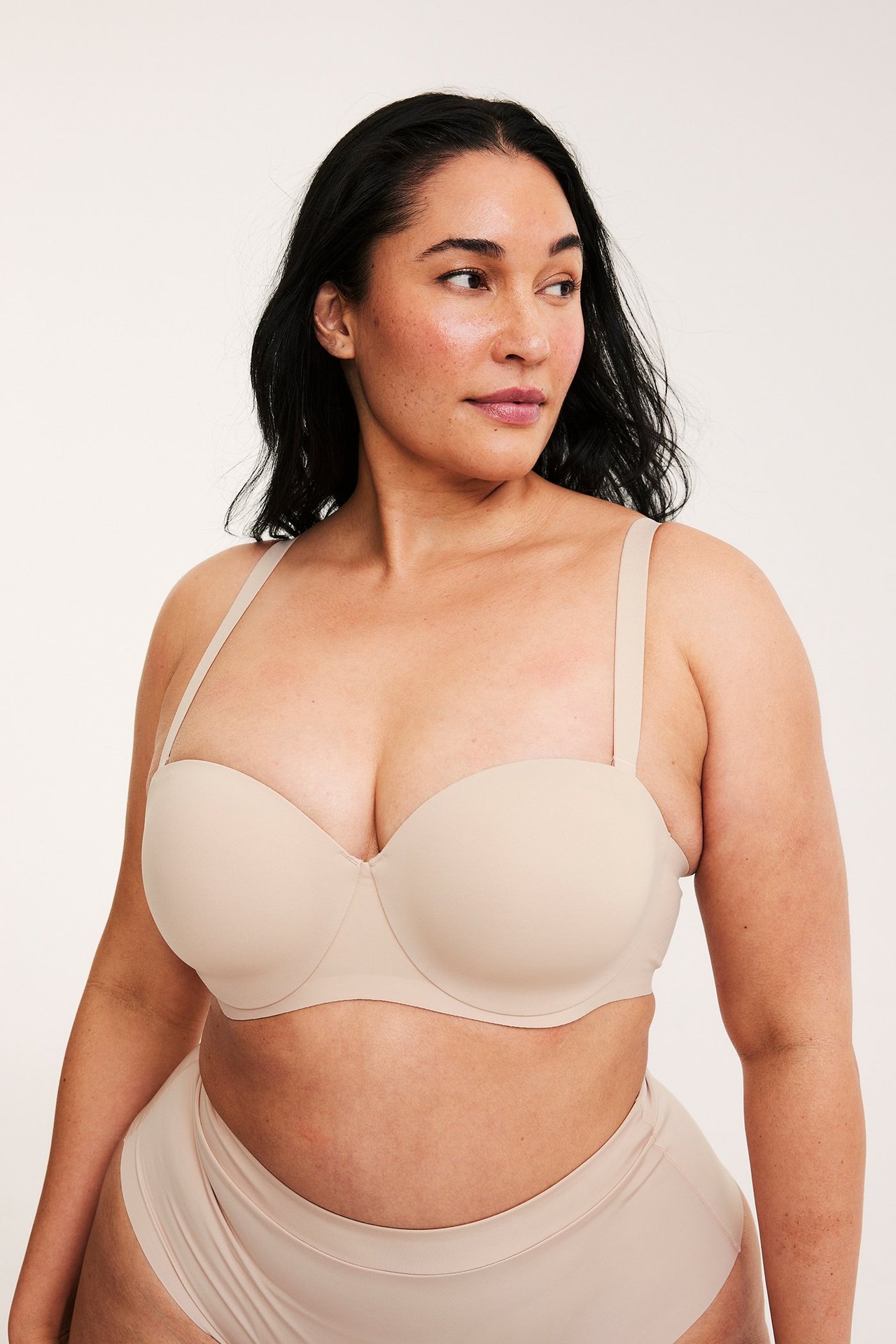 Widok z przodu: kobieta w jasnobeżowym biustonoszu balconette z ramiączkami i pasującymi majtkami.