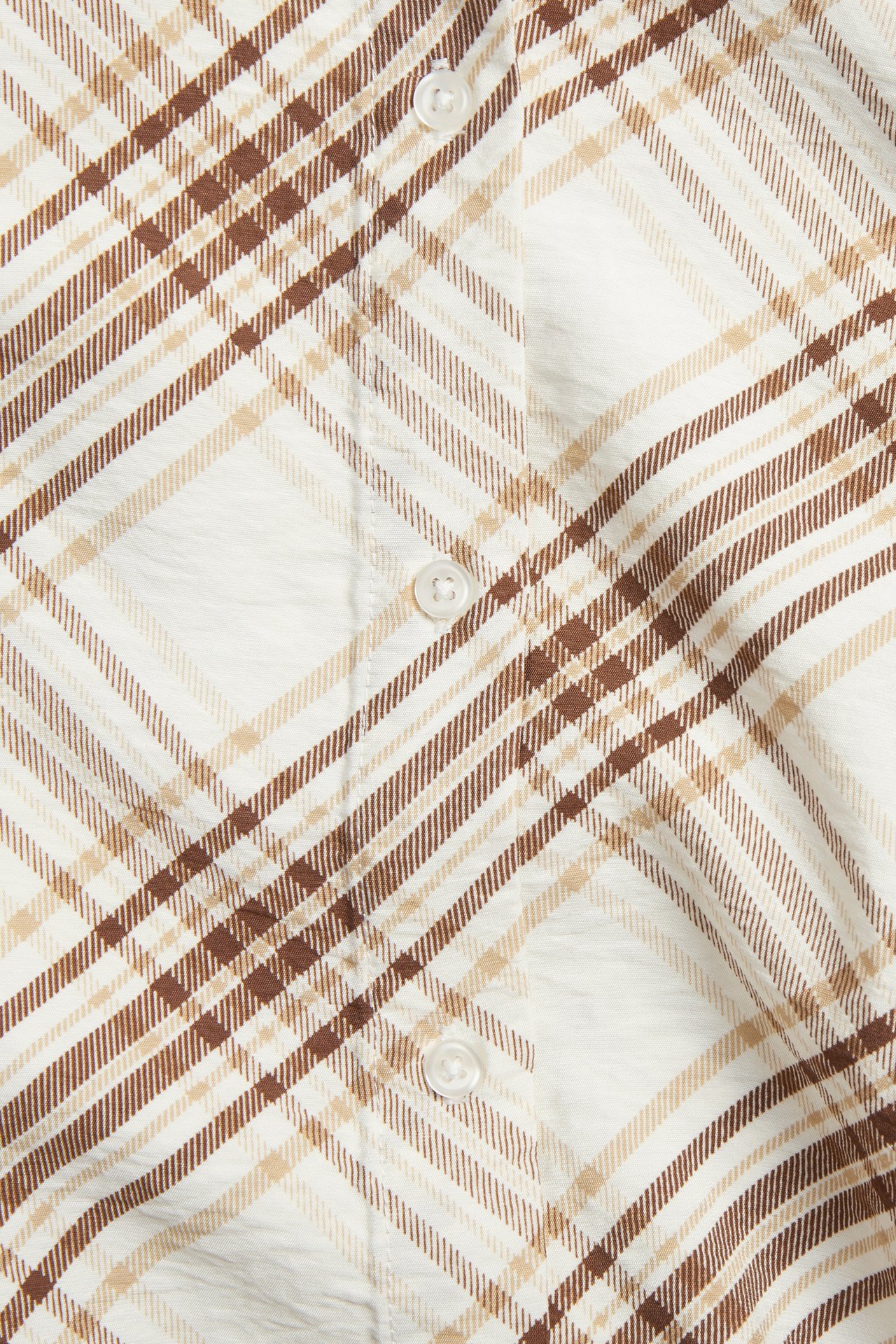 Närbild av en beige skjorta i viskosmix med brunt och beige rutigt mönster och vita knappar.