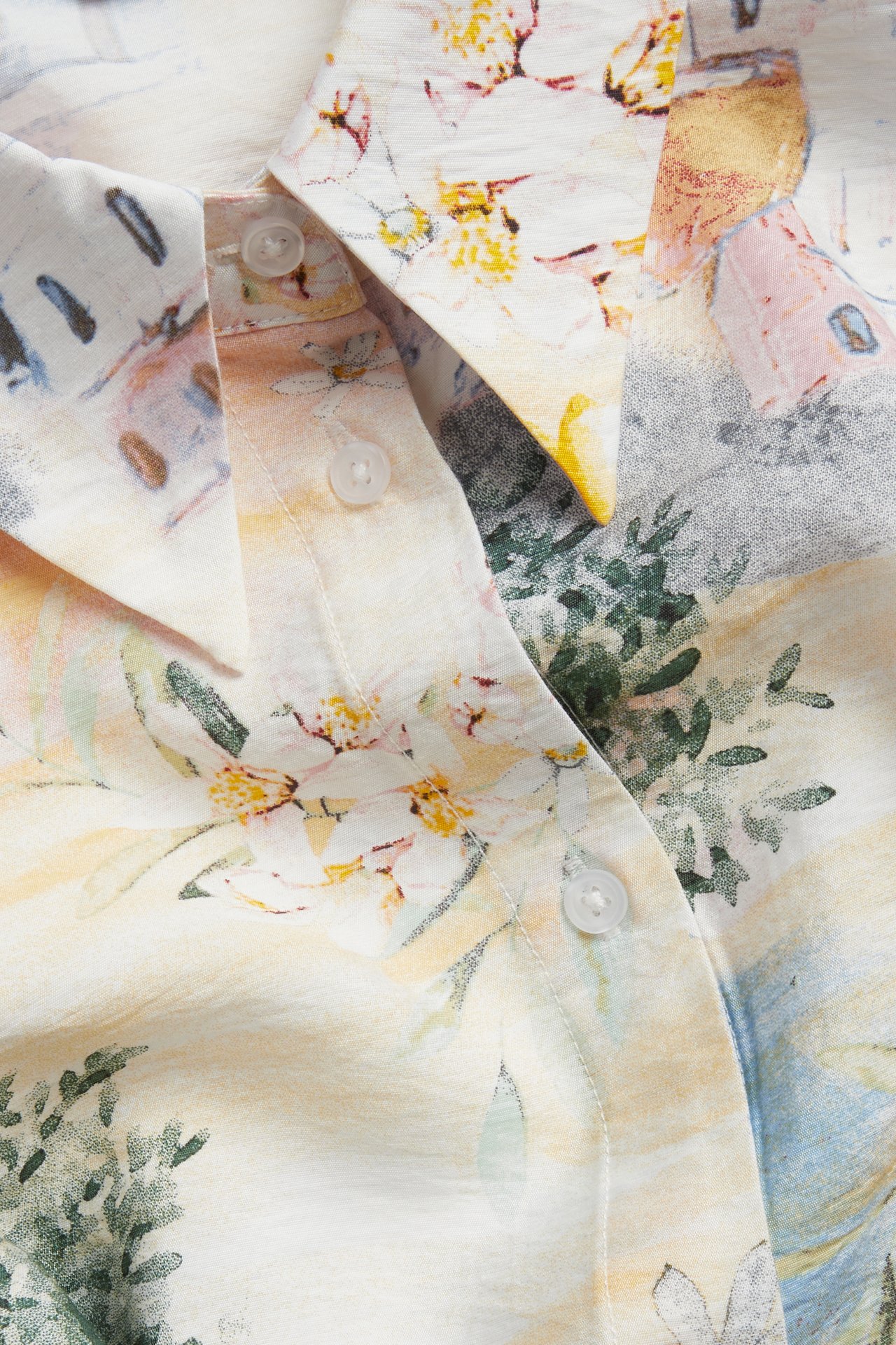 Närbild framifrån på offwhite skjorta i viskosmix med medelhavsmönster och vita knappar.