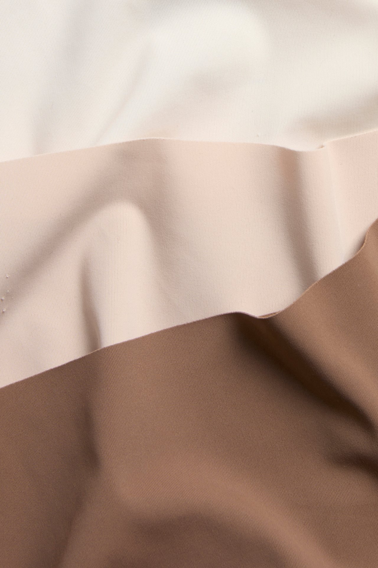 Närbild av trepaket med sömlösa stringtrosor i ljusbeige, nude och brun microfiber.