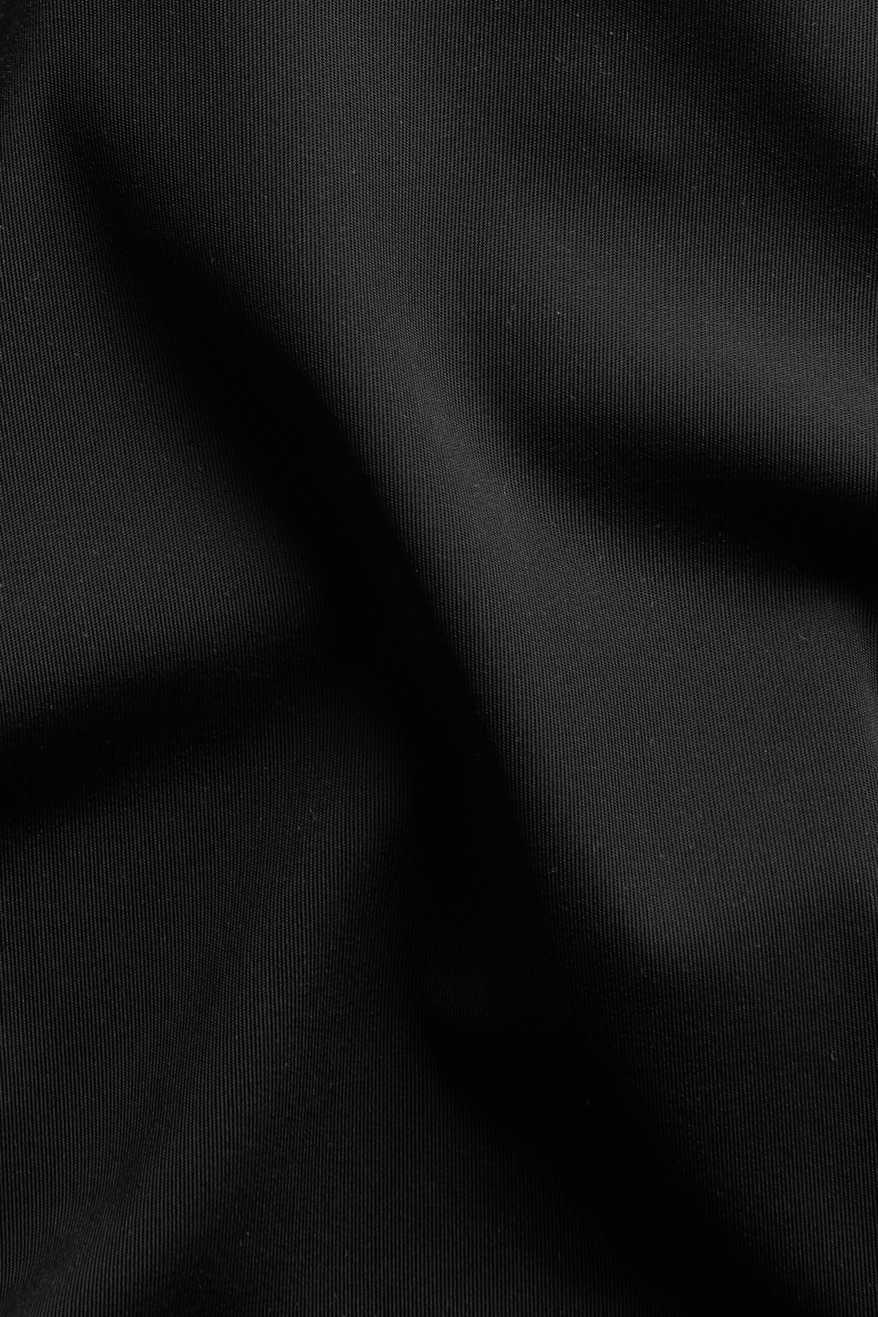 Närbild på svart, enfärgat microtyg med fin räfflad textur, avsett för hipstertrosor.