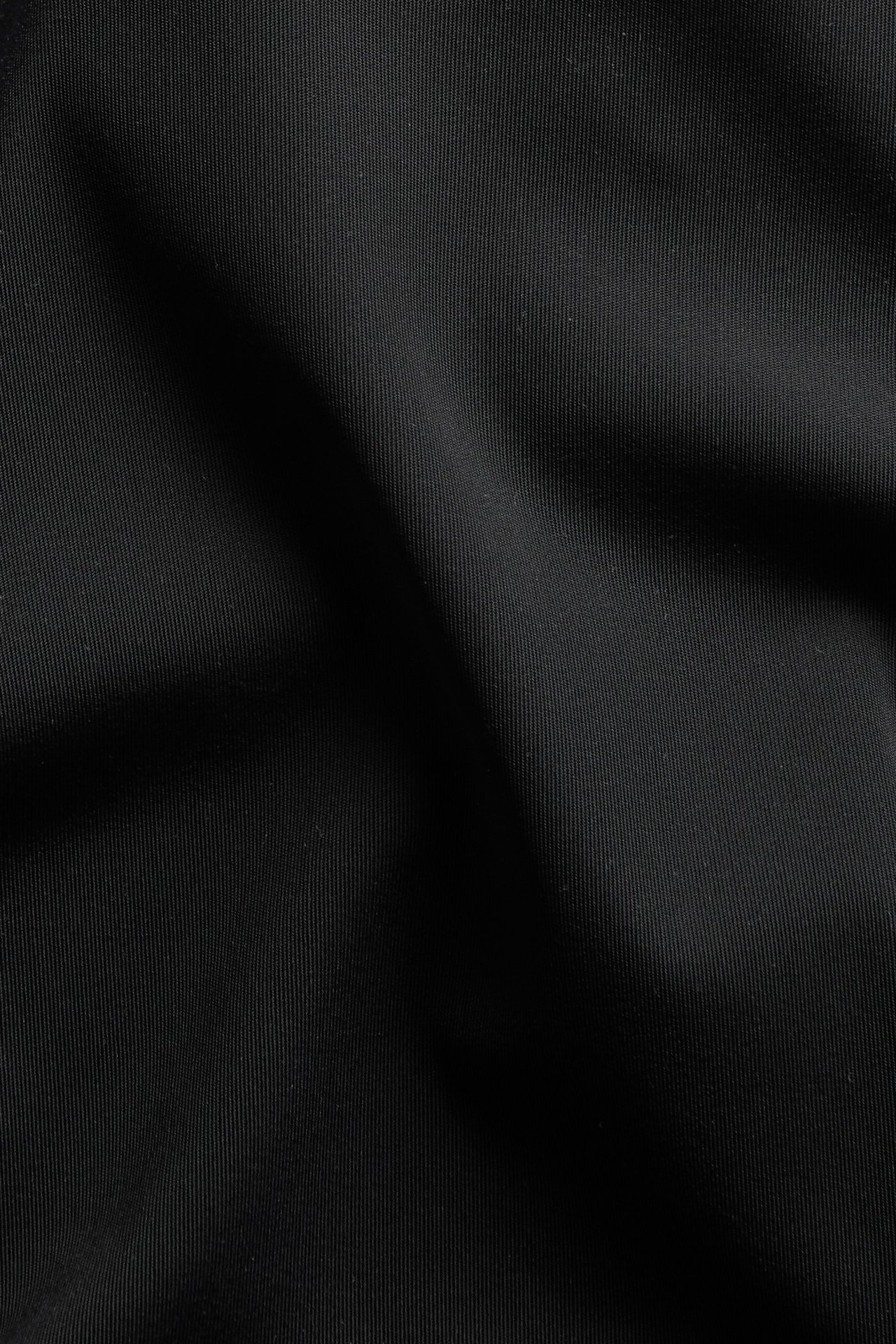 Närbild på svart, enfärgat microtyg med fin räfflad textur, avsett för hipstertrosor.