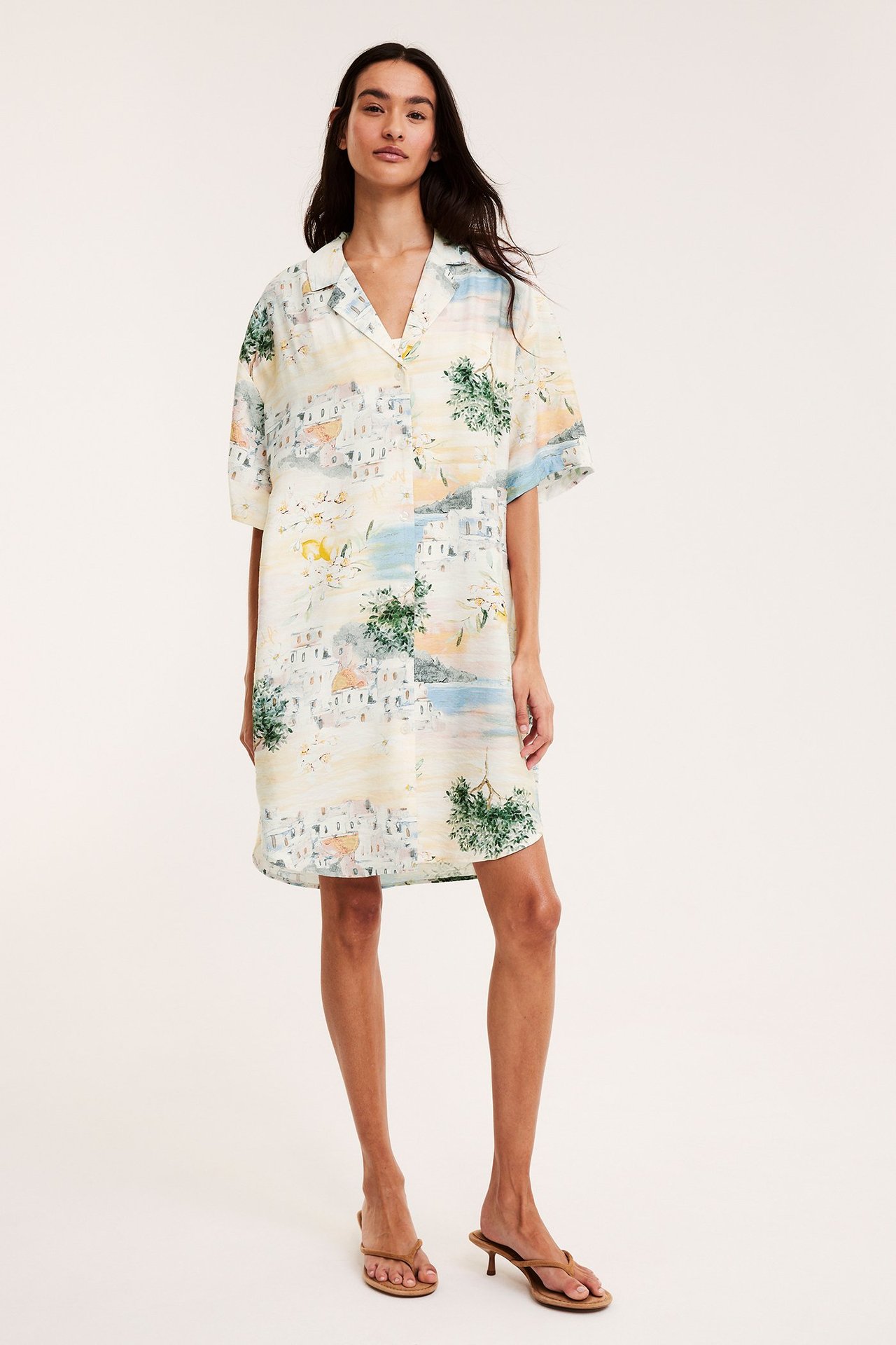 Framifrån: kvinna i mönstrad kortärmad skjortklänning i offwhite och bruna sandaler med klack.