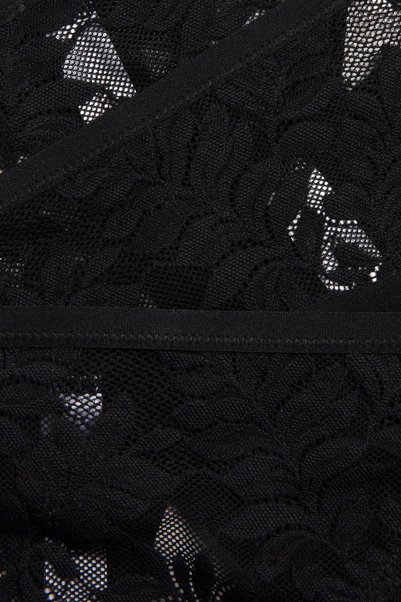 Närbild på svart spetstrosa med blommigt mönster och smal elastisk midja.