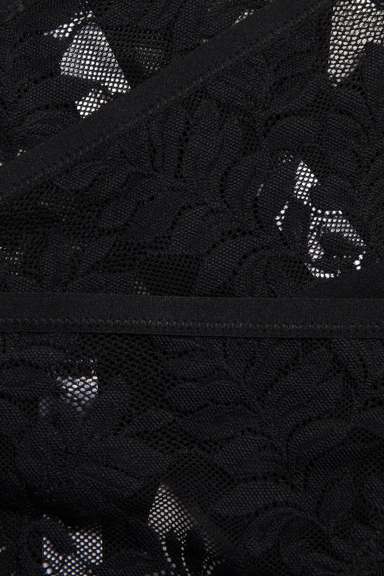 Närbild på svart spetstrosa med blommigt mönster och smal elastisk midja.