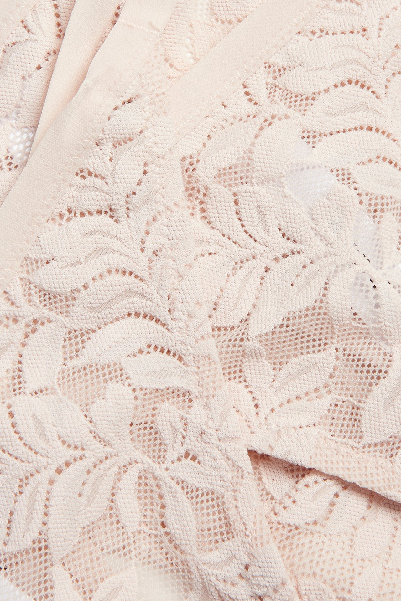 Närbild av ljusrosa spetsstringtrosor med ett delikat blommönster.