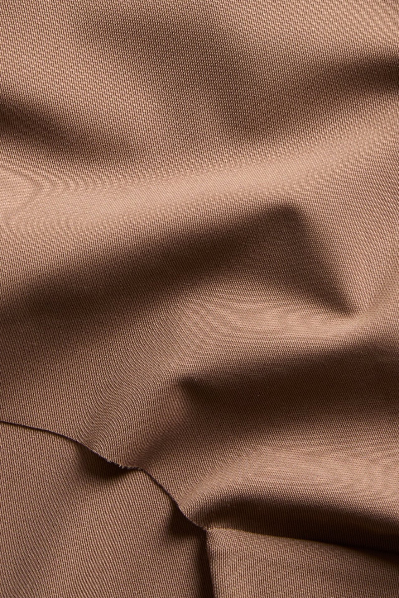 Nærbilde av brunt, ensfarget mikrostoff til hipster-truse, med subtil tekstur og folder.