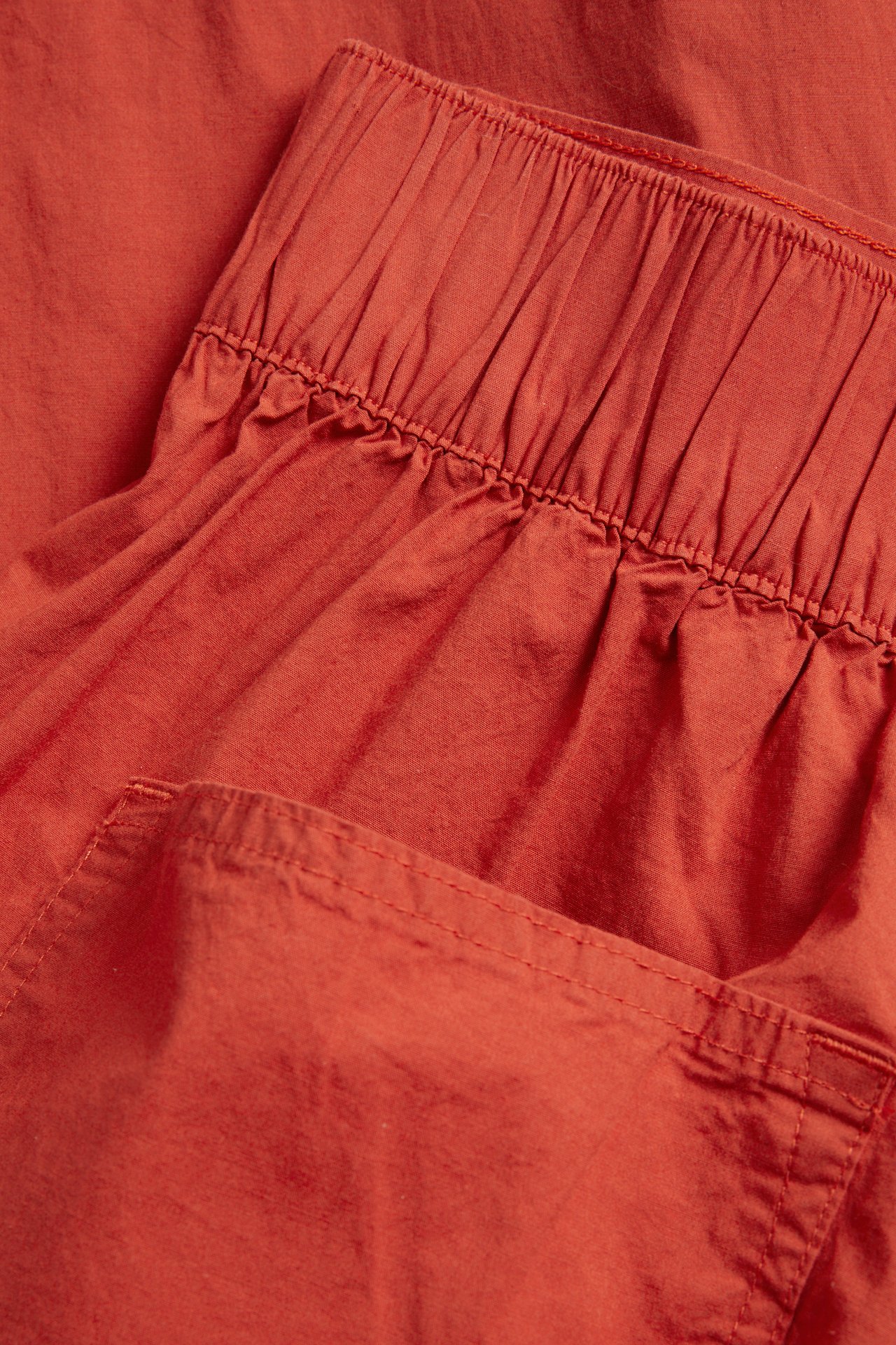 Lähikuva punaisista barrel fit -popliinihousuista, joissa joustava vyötärö ja sivutasku.