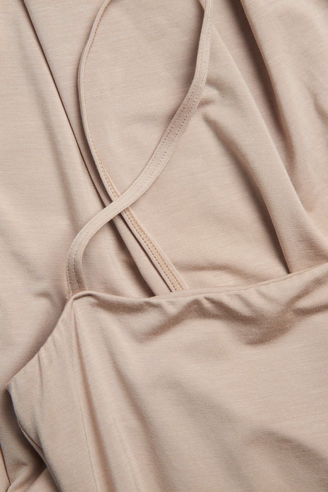 Närbild på en ljusbrun underklänning i lyocellmix med tunna justerbara axelband.