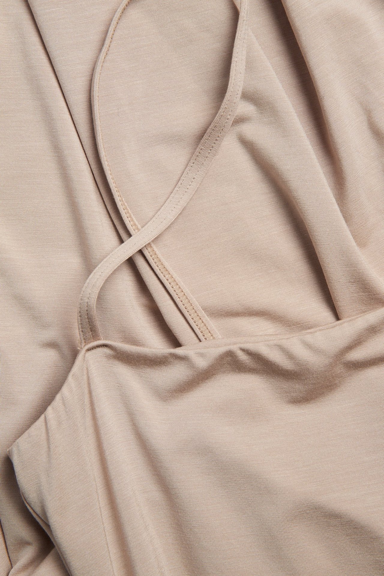 Närbild på en ljusbrun underklänning i lyocellmix med tunna justerbara axelband.