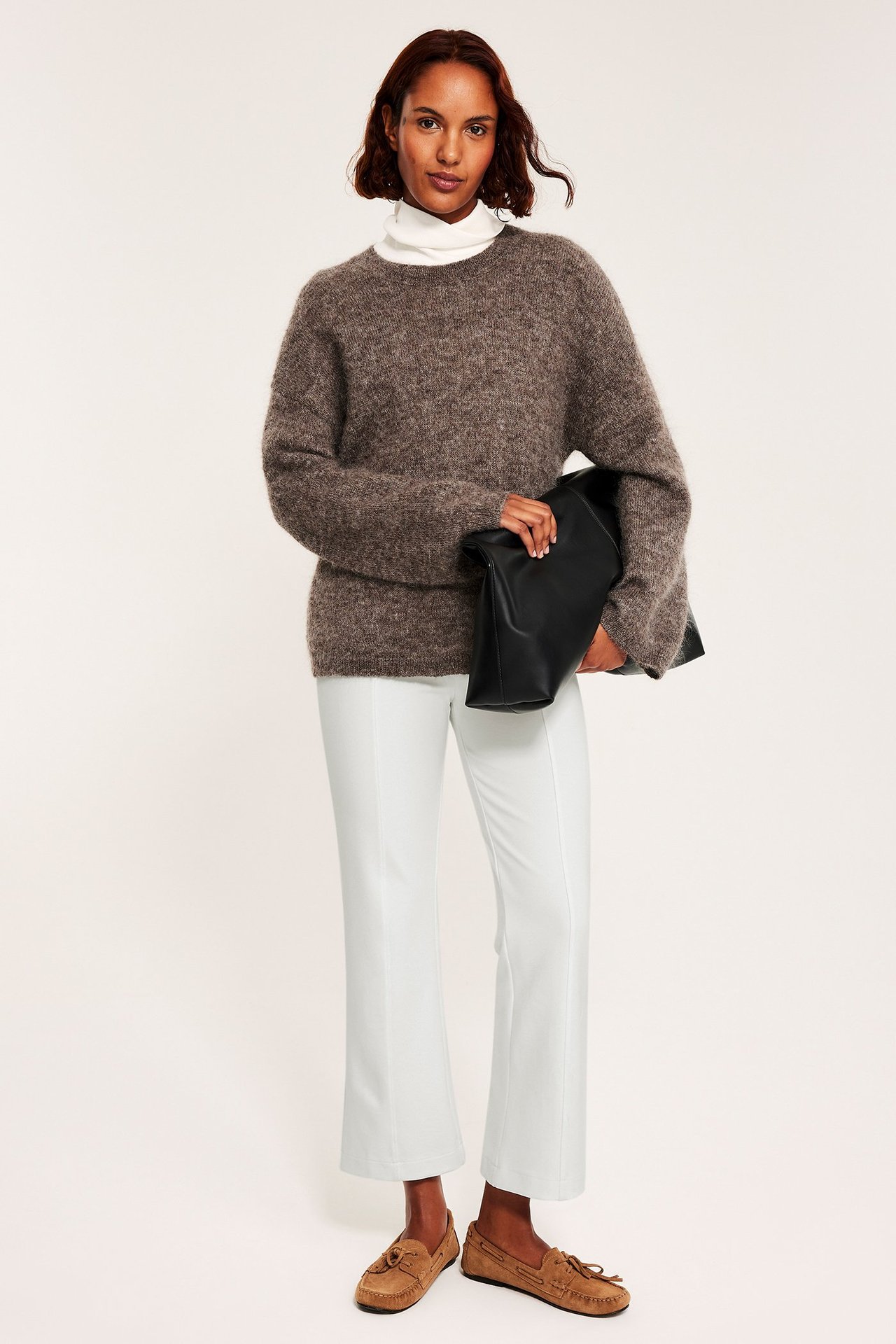 Nainen offwhite-sävyisissä saumurillisissa housuissa, neulepaita ja loafers, etunäkymä.