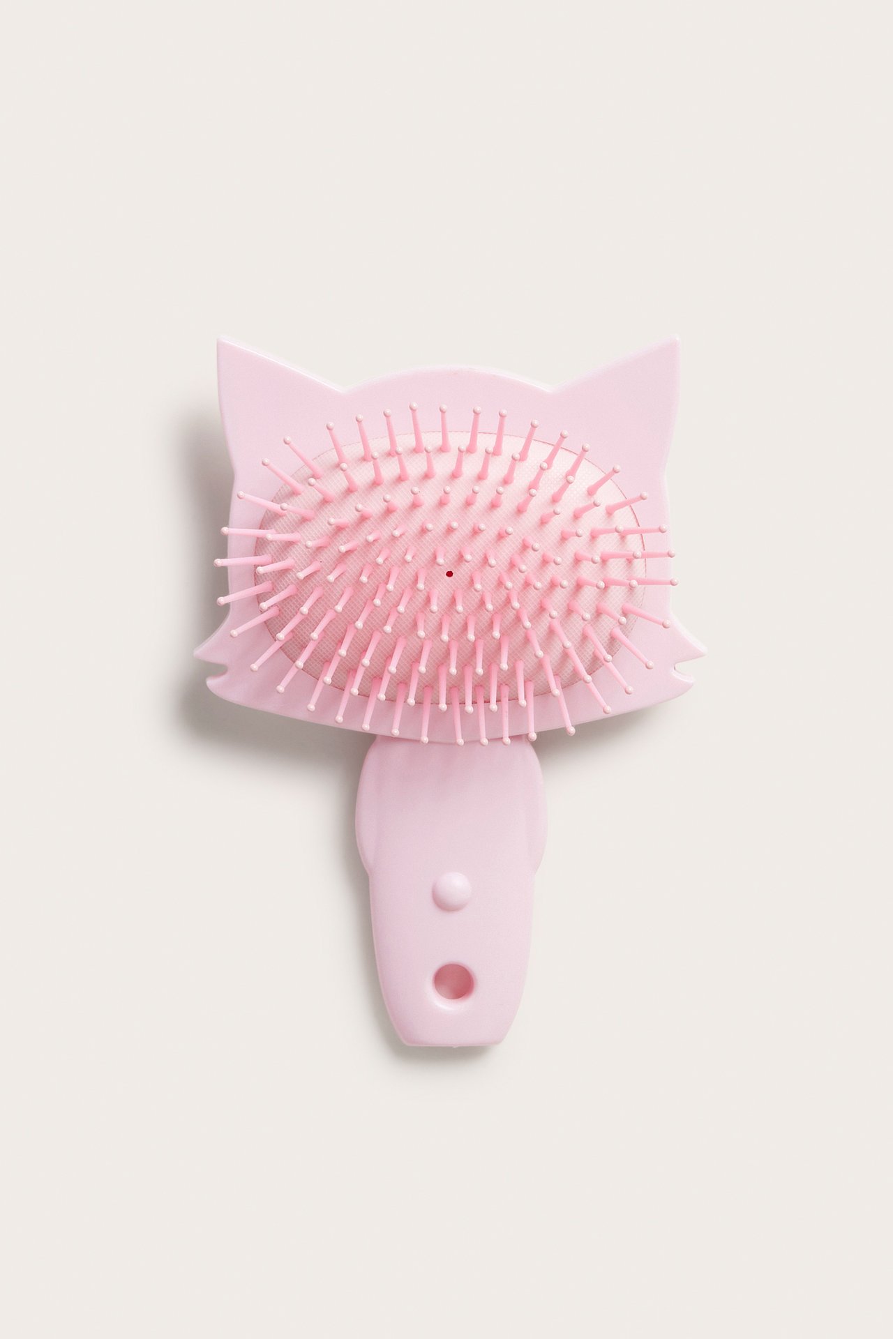 Zbliżenie na różową plastikową szczotkę do włosów w kształcie kociej głowy z różowym włosiem i rączką.