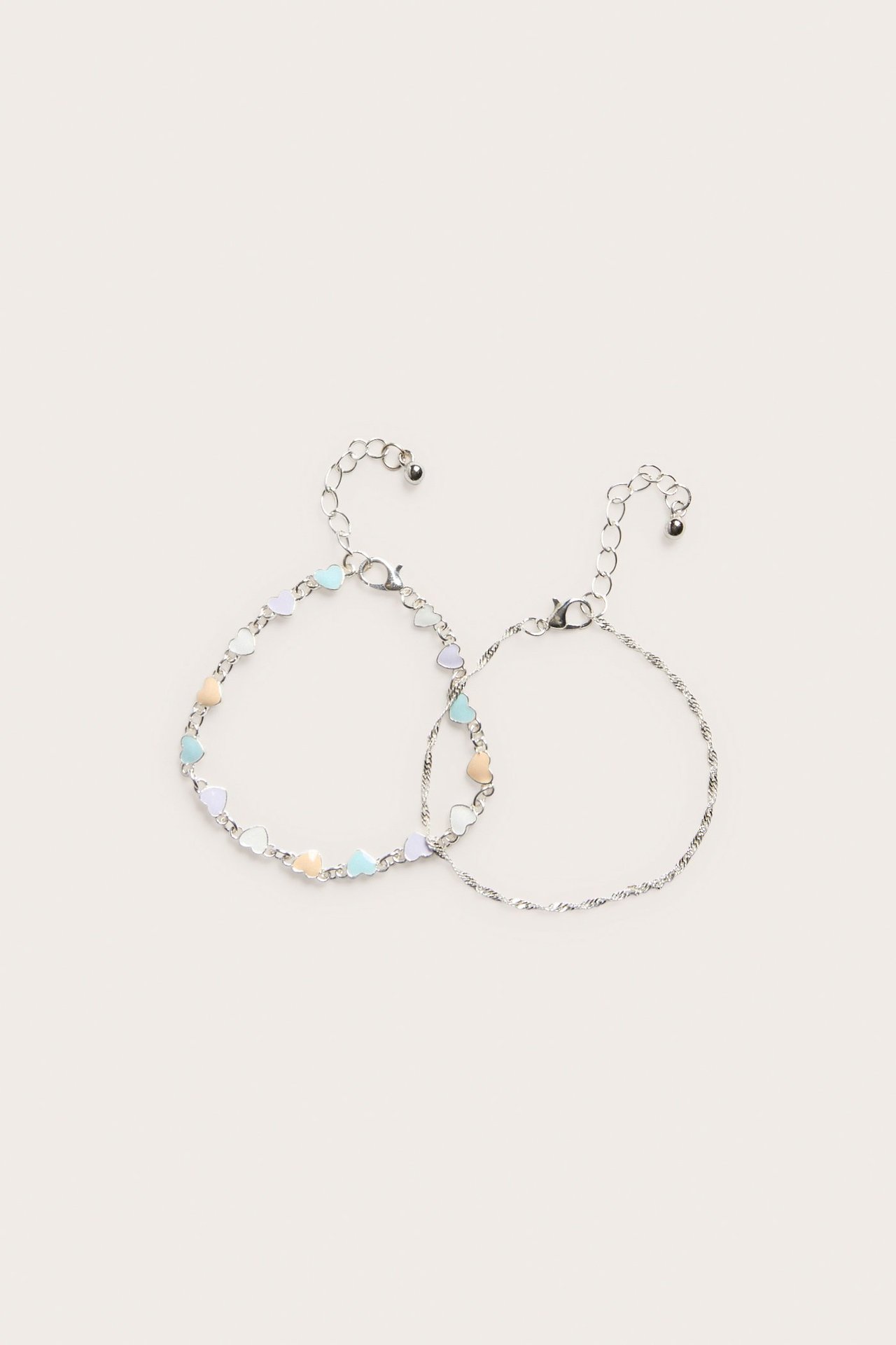 Dwie srebrne bransoletki: jedna z pastelowymi serduszkami, druga skręcana, obie z zapięciem.