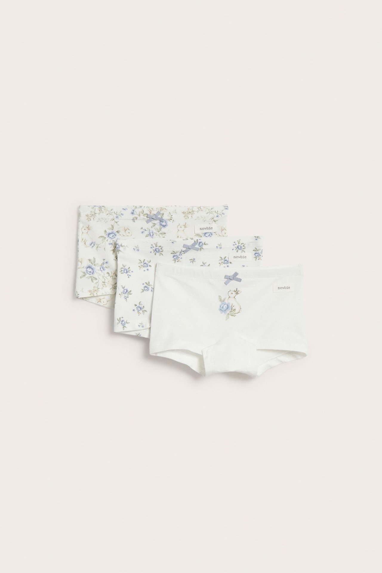 Frontbilde av tre offwhite barne-boxershortser med blått blomster- og kaninmønster, hver med sløyfe.
