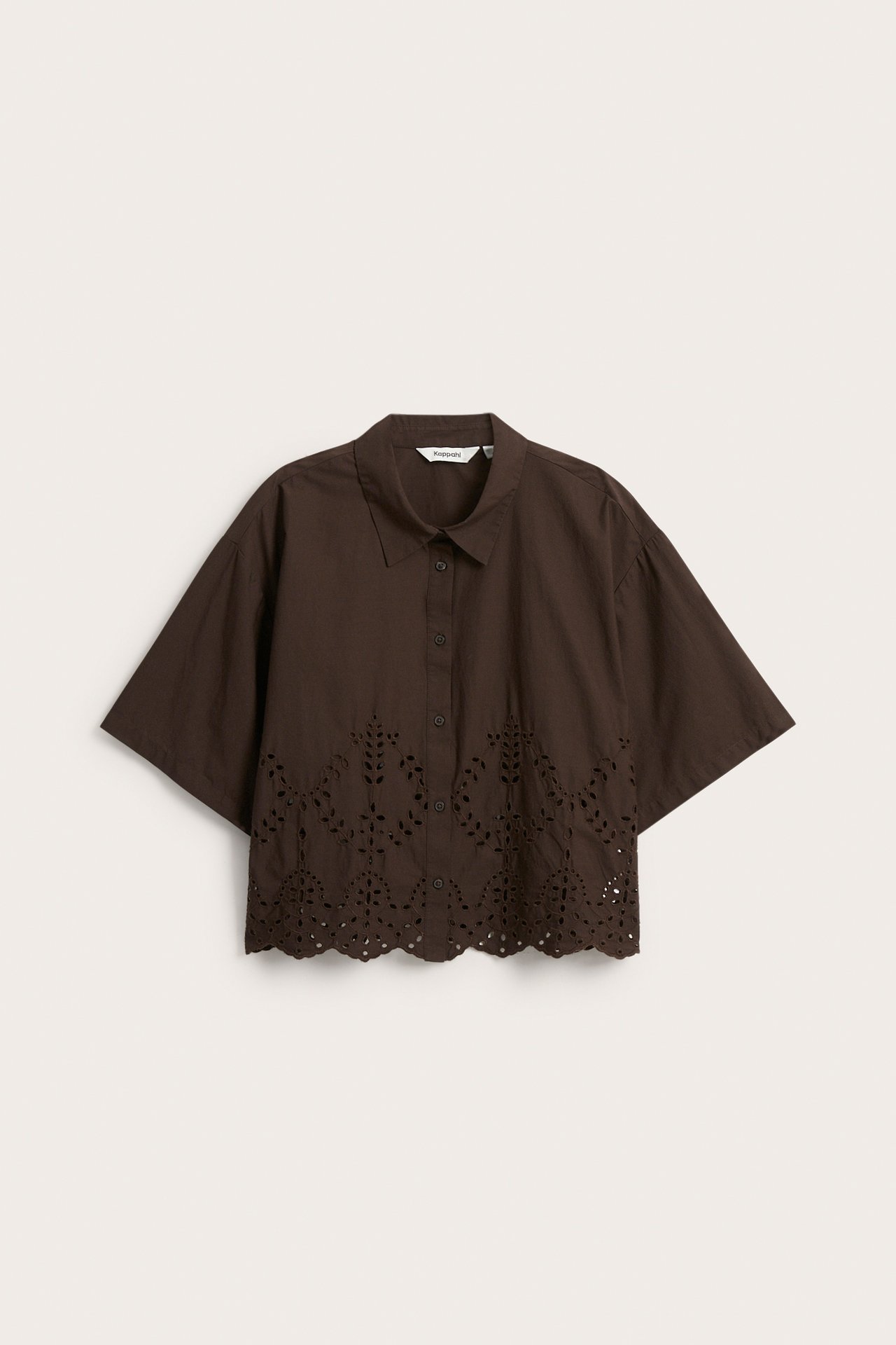 Frontvisning av en brun kortermet bomullsskjorte med knapper og broderie anglaise-detaljer langs kanten.