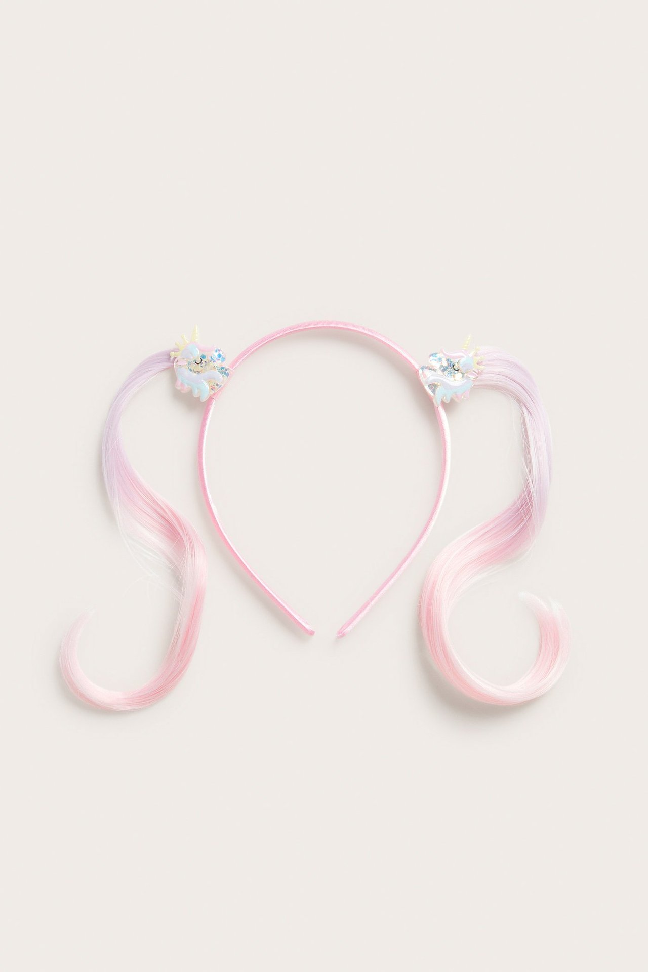 Widok z góry: jasnoróżowa opaska z jednorożcami i falowanymi różowo-fioletowymi włosami syntetycznymi.