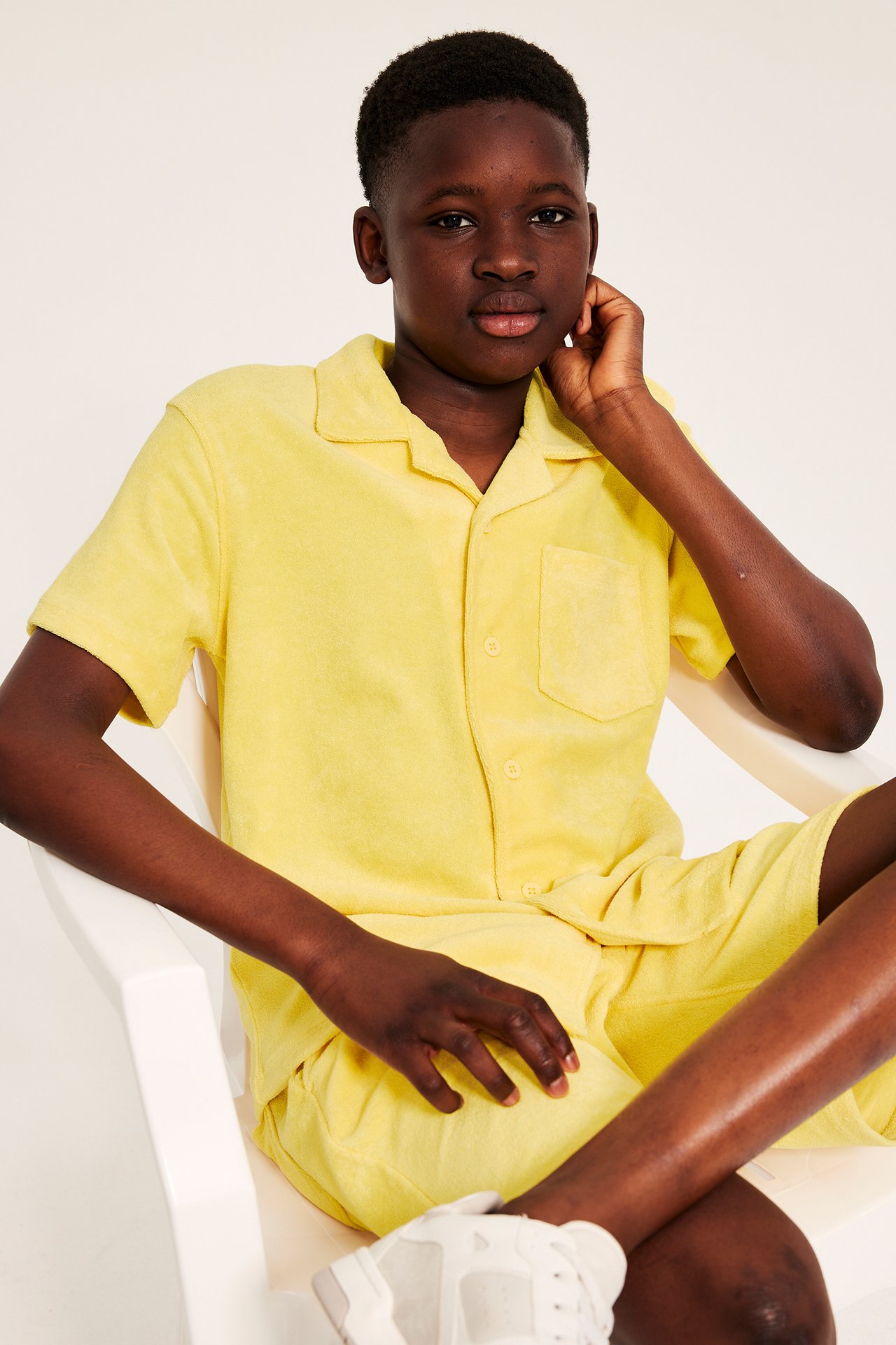 Frontvy av ett barn i gul kortärmad frottéskjorta med resortkrage och matchande shorts.