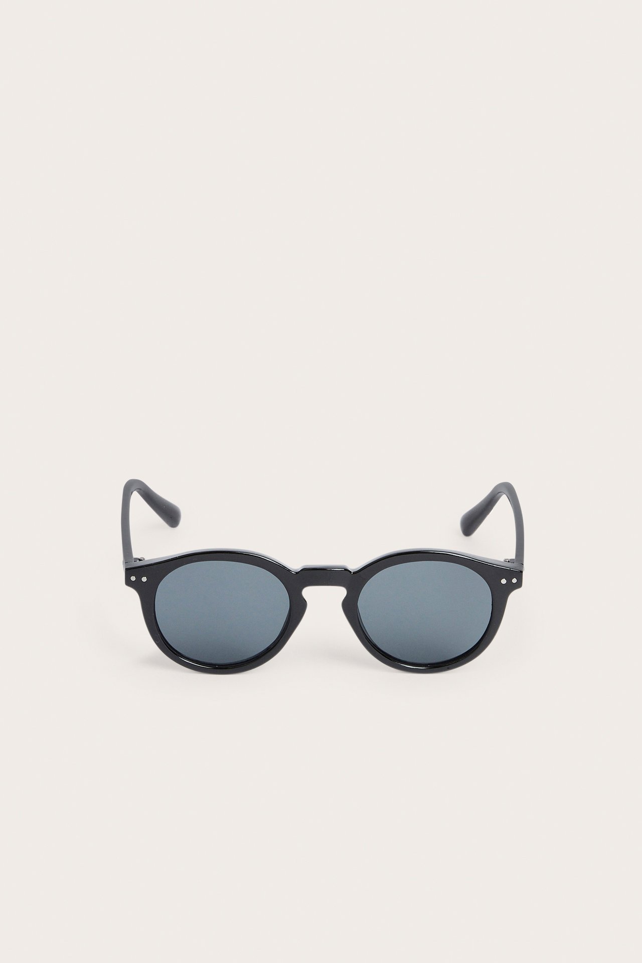 Edestä mustat pyöreät muoviset aurinkolasit.