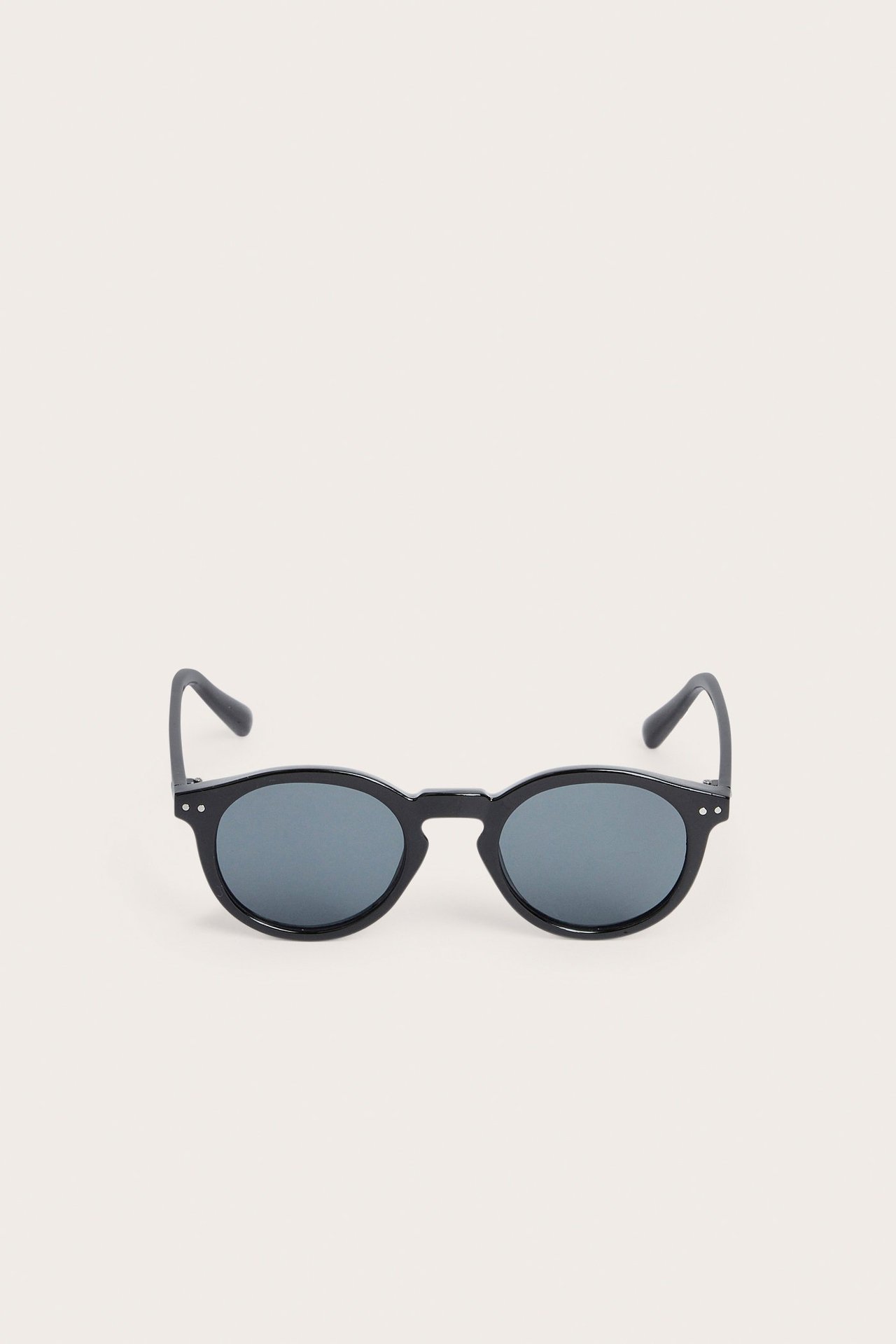 Edestä mustat pyöreät muoviset aurinkolasit.