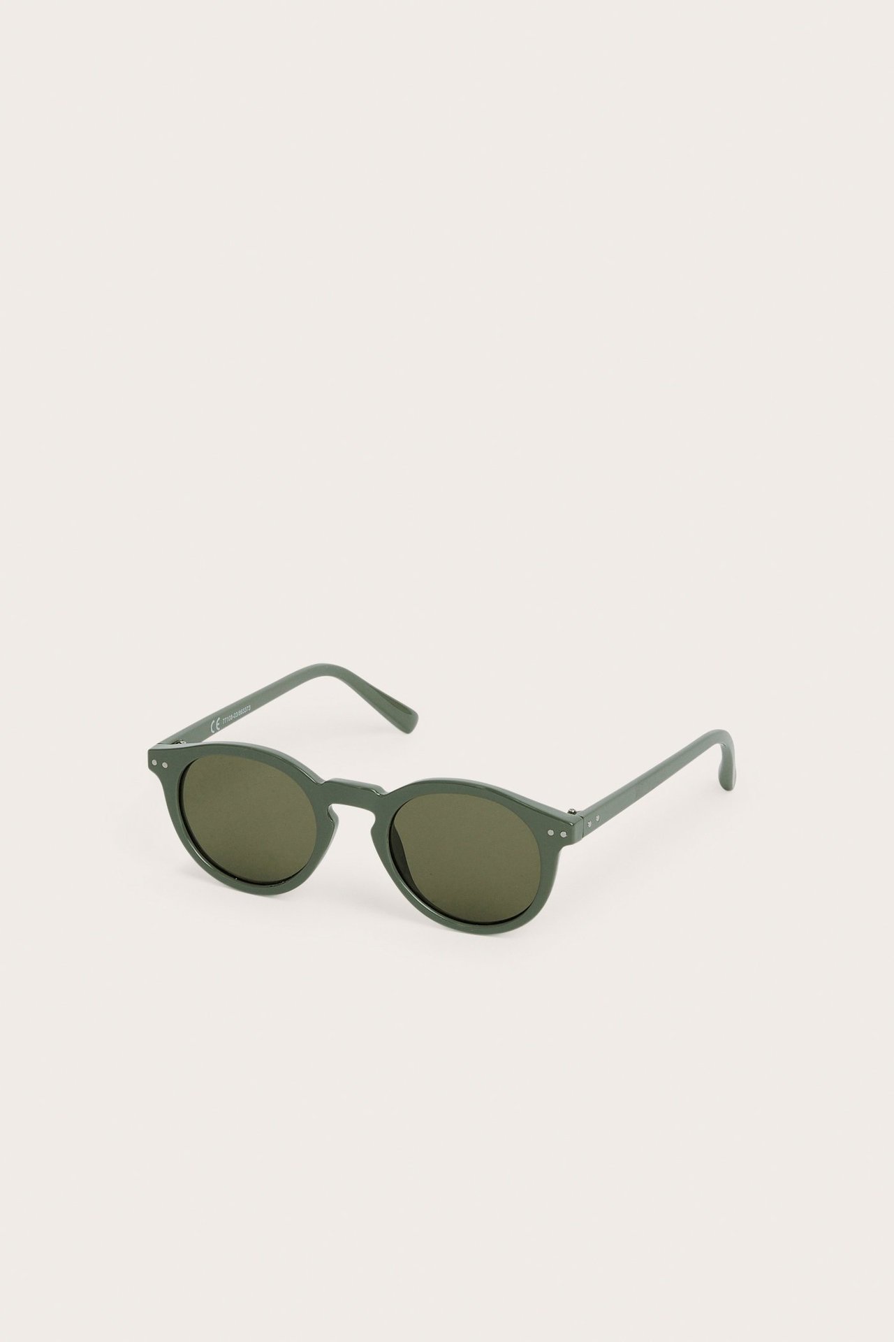 Edestä näkymä yksivärisistä vihreistä muovisista pyöreistä aurinkolaseista tummilla linsseillä.