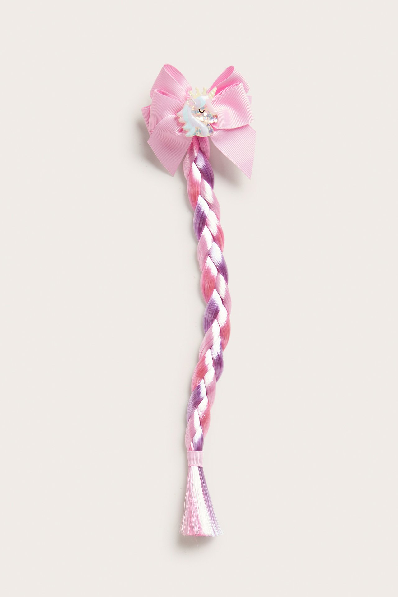 Widok z przodu różowej spinki do włosów z kokardą, jednorożcem i długim różowym, fioletowym, białym warkoczem.