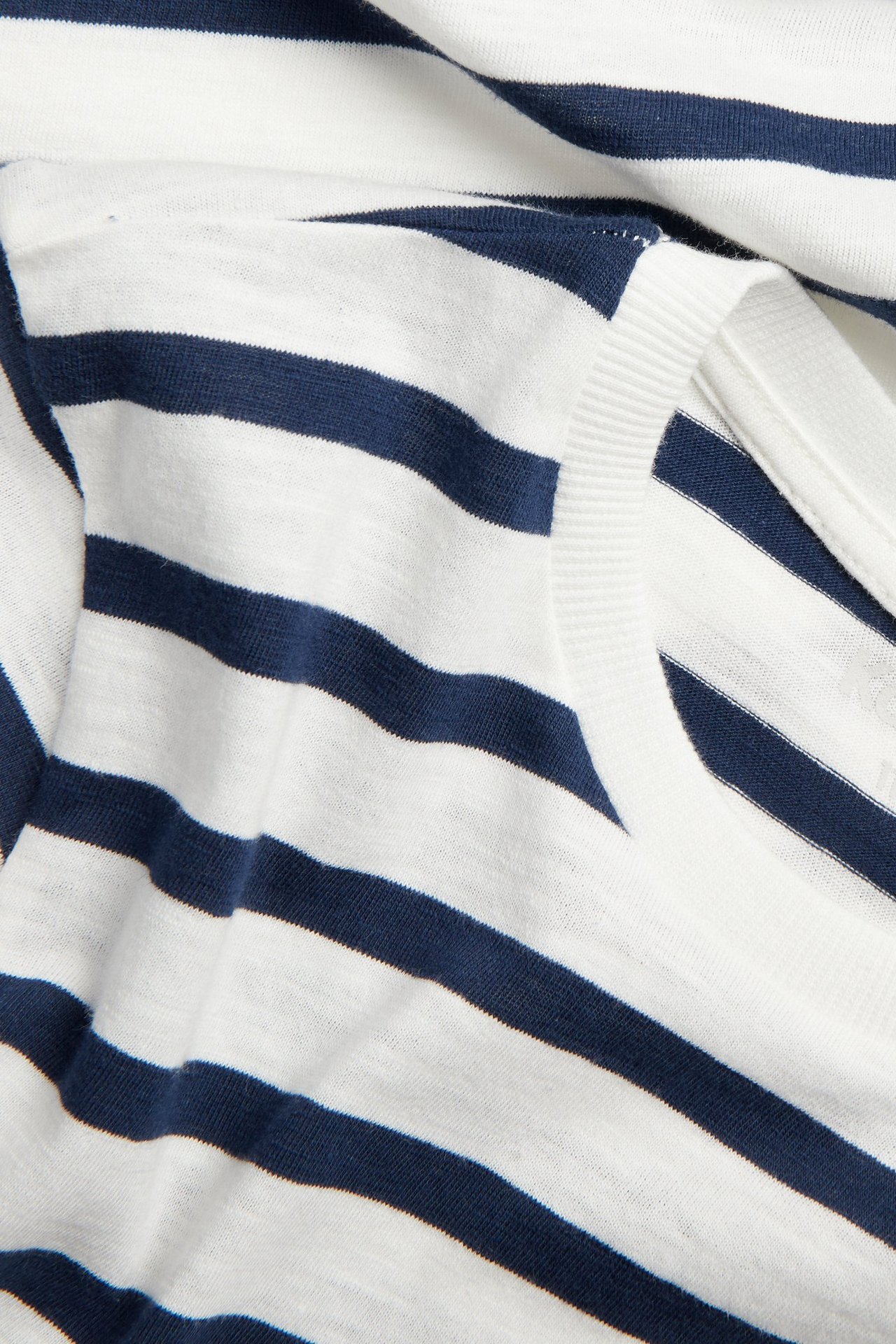 Närbild av en randig t-shirt för barn i mörkblå och vit bomull med ribbad halsringning.