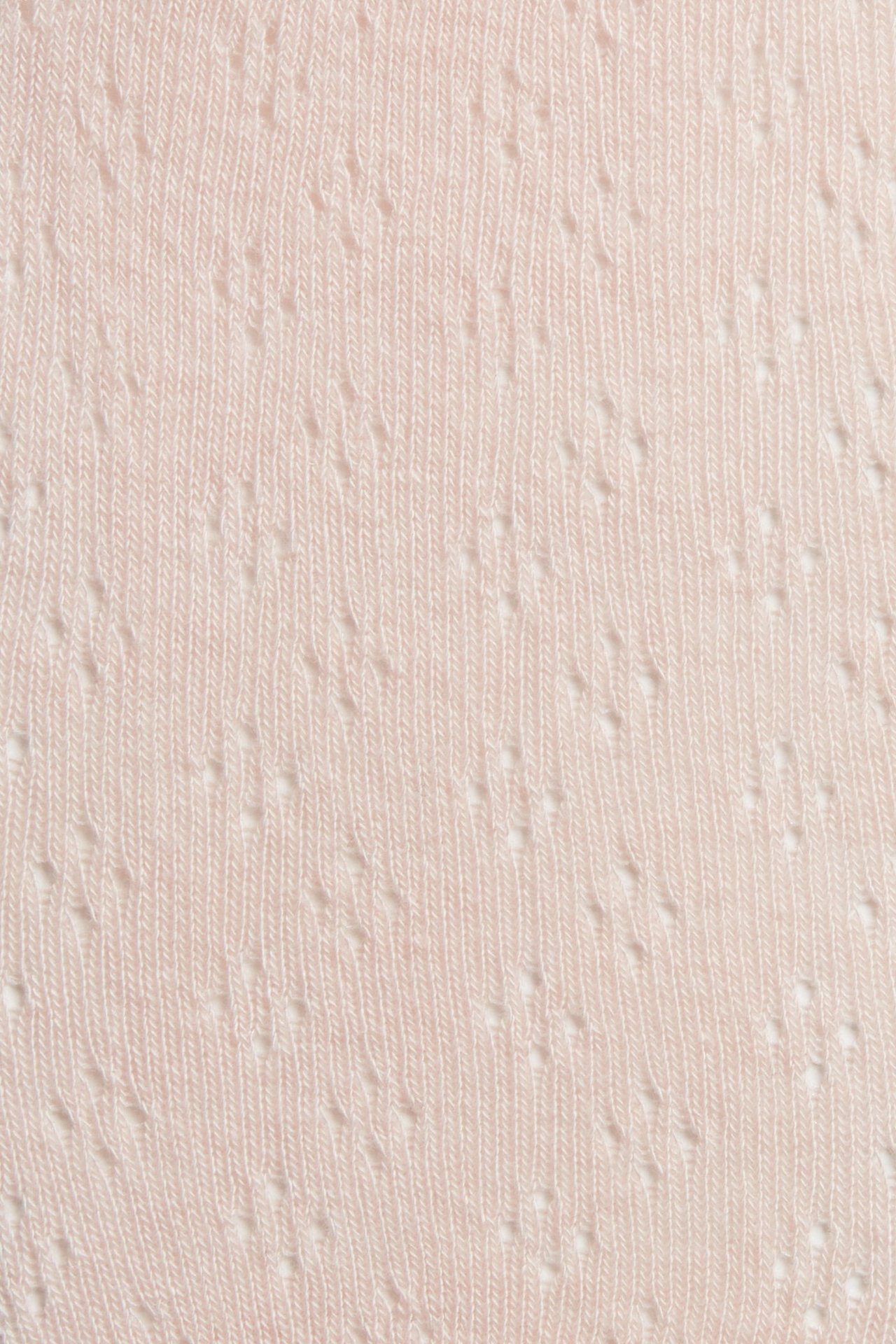 Zbliżenie na jasnoróżowe rajstopy z dzianiny z ażurowym wzorem.