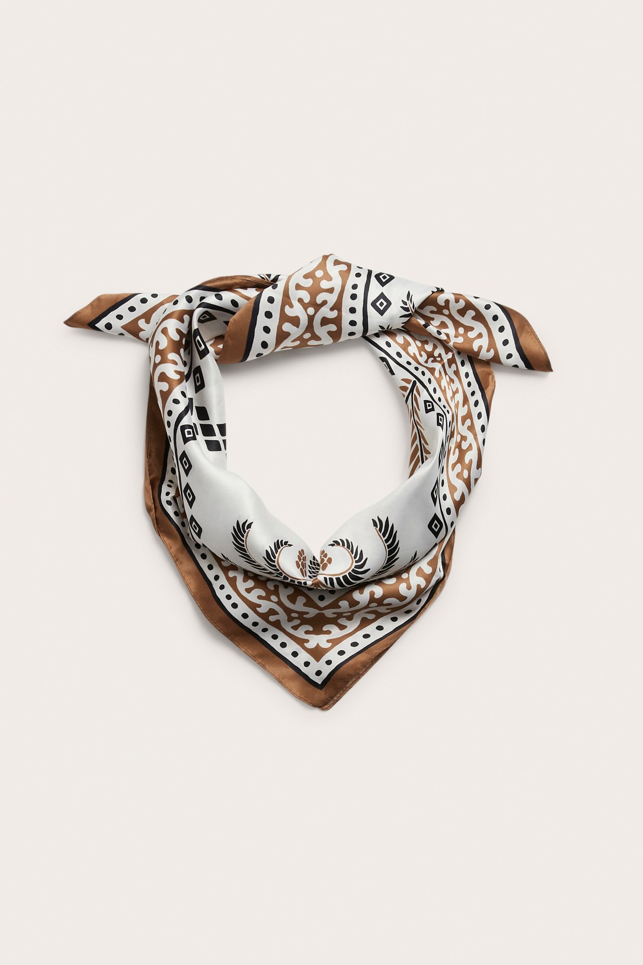 Edestäpäin kuvattu solmittu neliönmuotoinen polyesterihuivi ruskealla, valkoisella ja mustalla kuviolla.