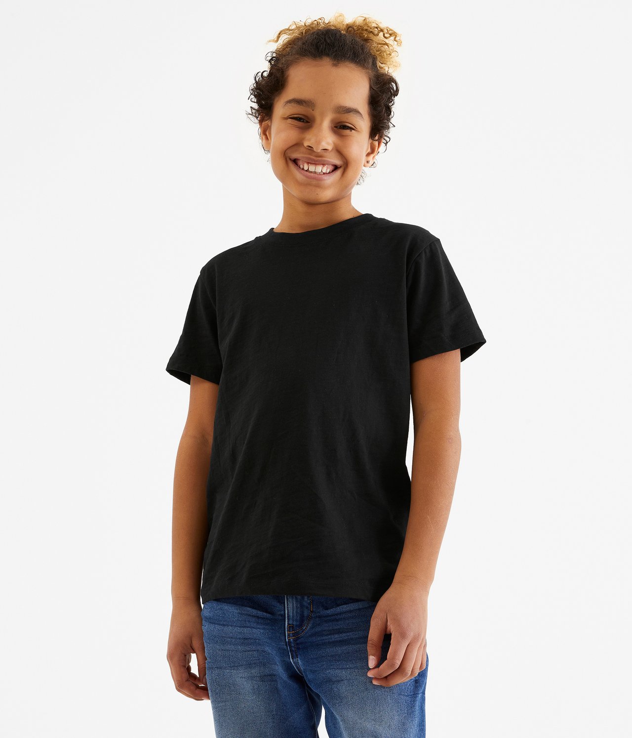 Framifrån, leende barn i en enfärgad svart bomulls-T-shirt och blå jeans.
