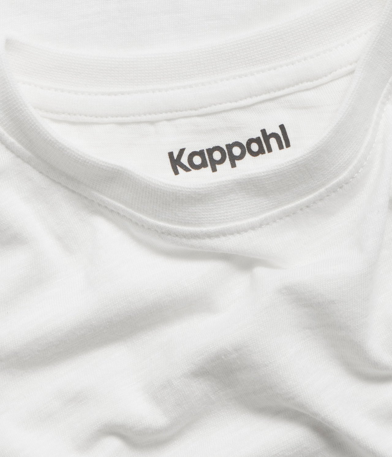 Zbliżenie na dekolt bawełnianego T-shirtu w kolorze złamanej bieli z widoczną metką marki.