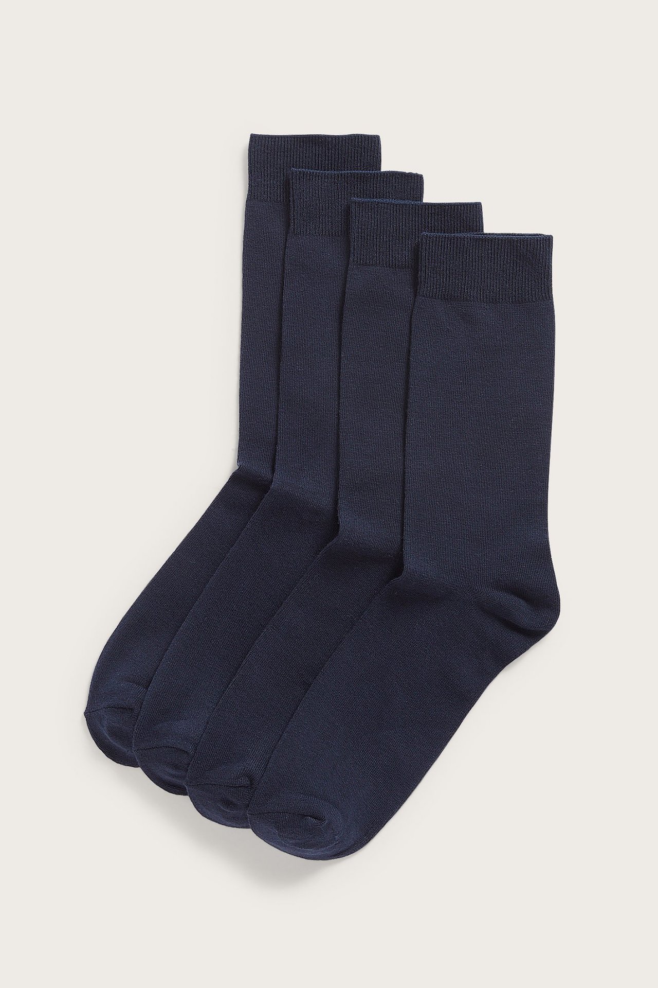 Framsida av fyra mörkblå slätstickade strumpor med mjuk, ribbad resår.