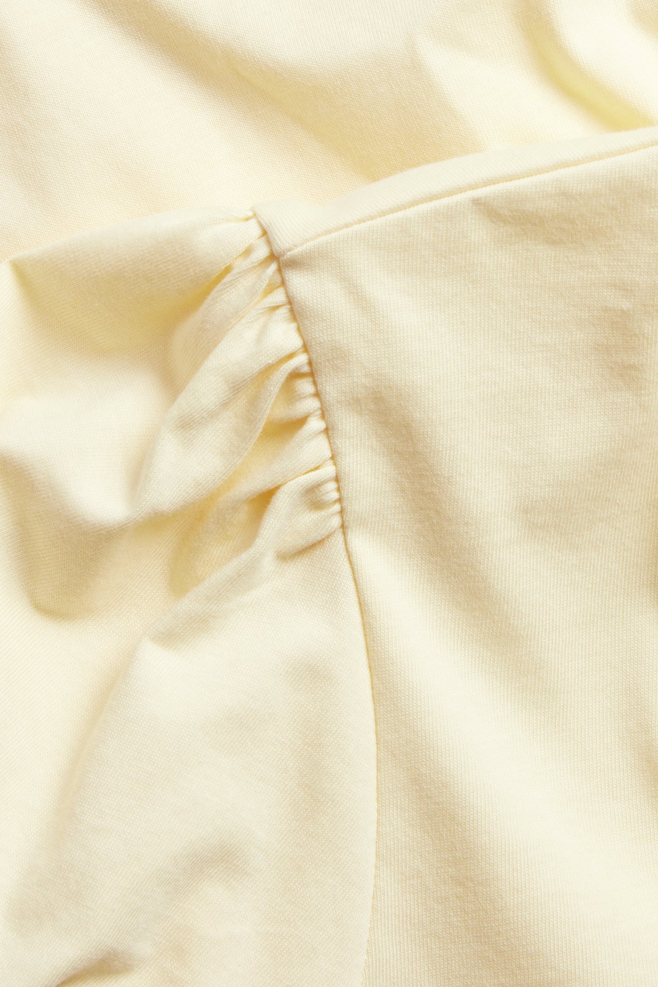 Nærbilde av en lys gul bomullstopp med rynket pufferme-detalj.