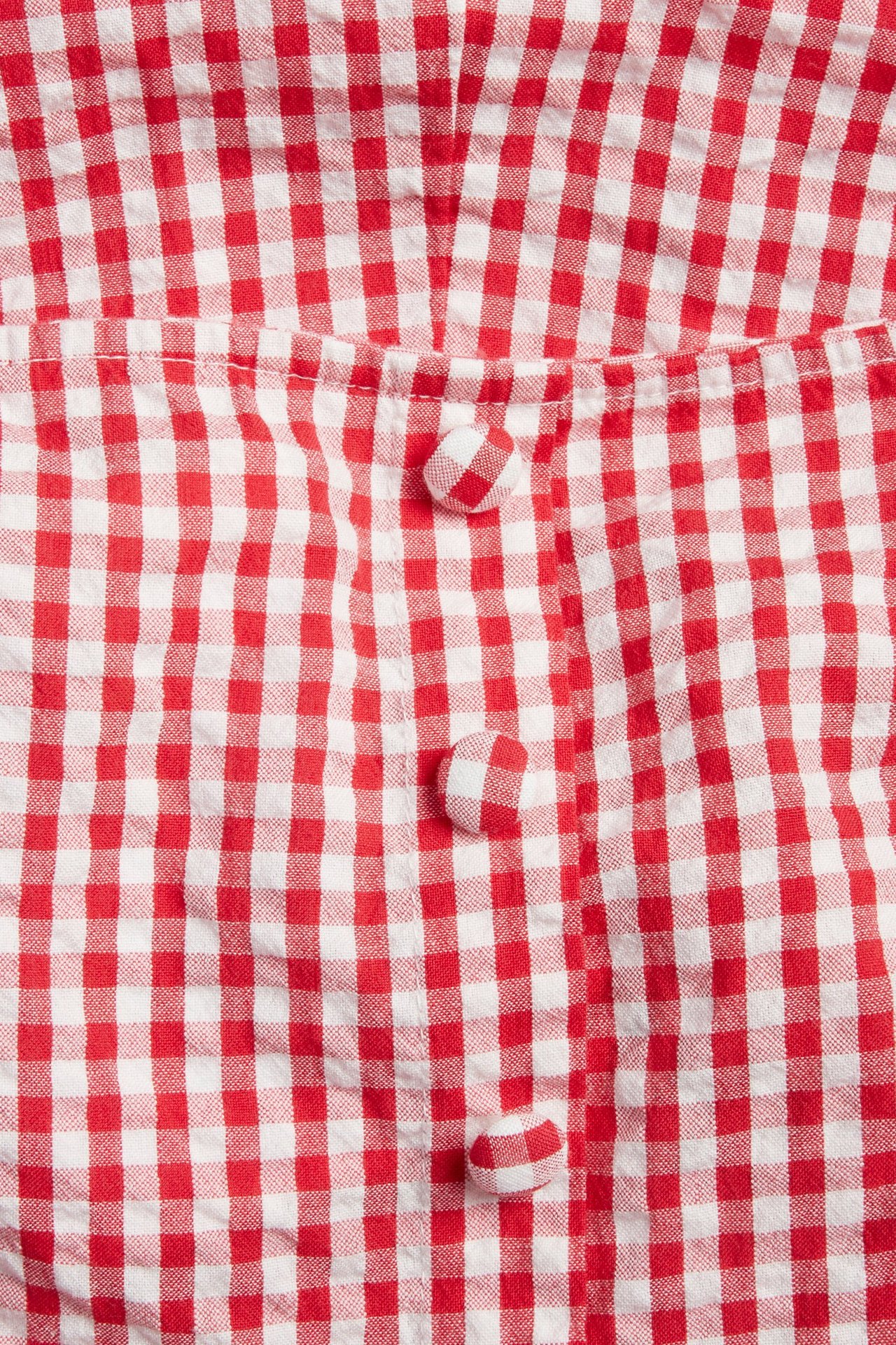 Lähikuva punavalkoruudullisesta seersucker-mekosta, jossa on yhteensopivat päällystetyt napit.
