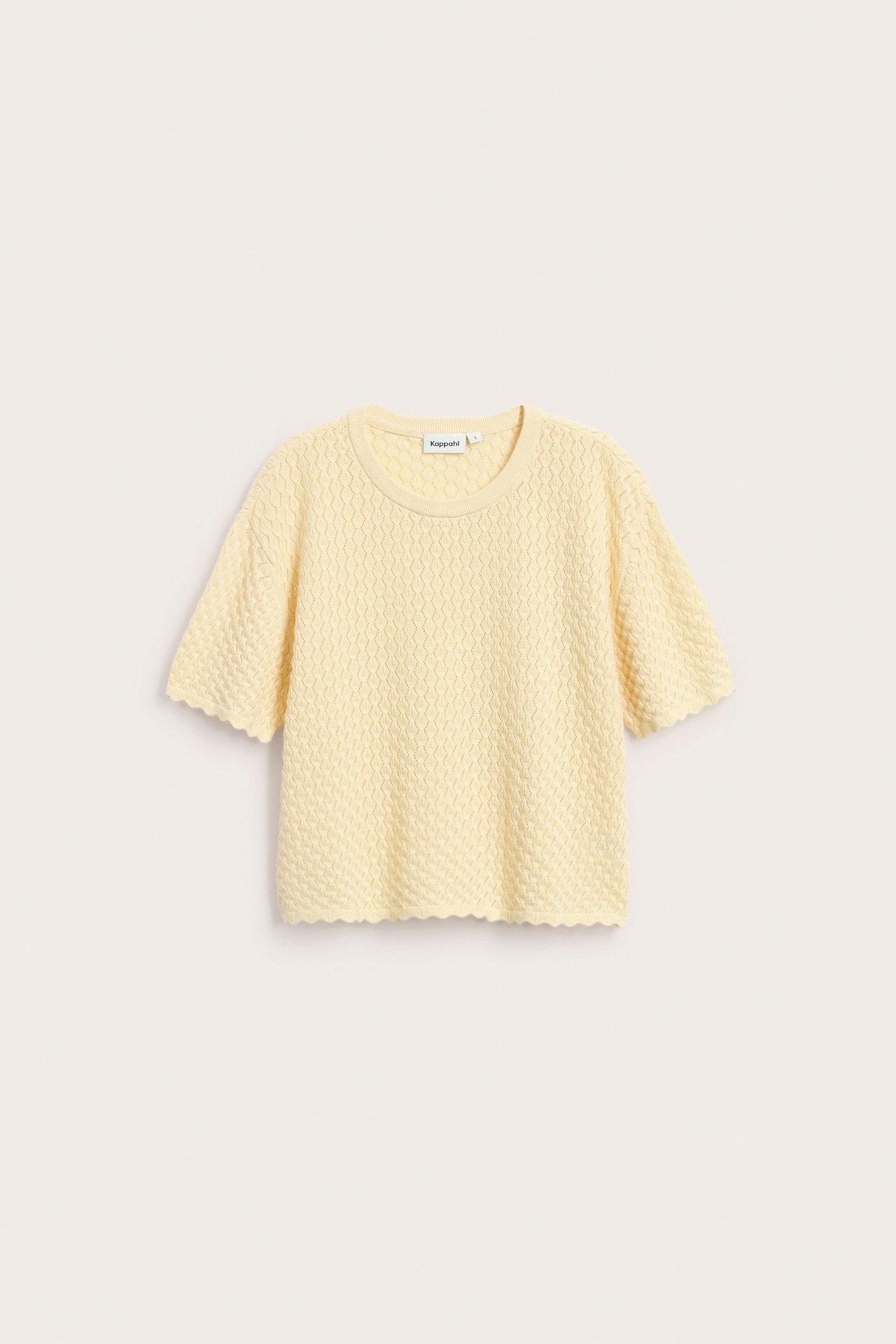 Przód jasnożółtego krótkiego swetra z dzianiny o teksturowanym wzorze i falistych brzegach.