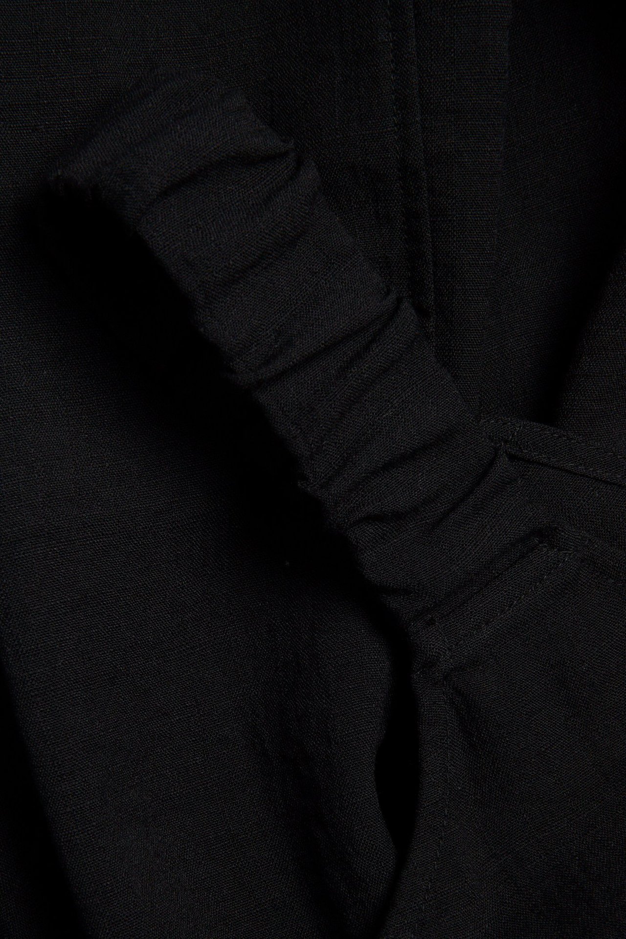 Nærbilde av en svart lang kjole i viskoseblanding med rynket stroppdetalj.