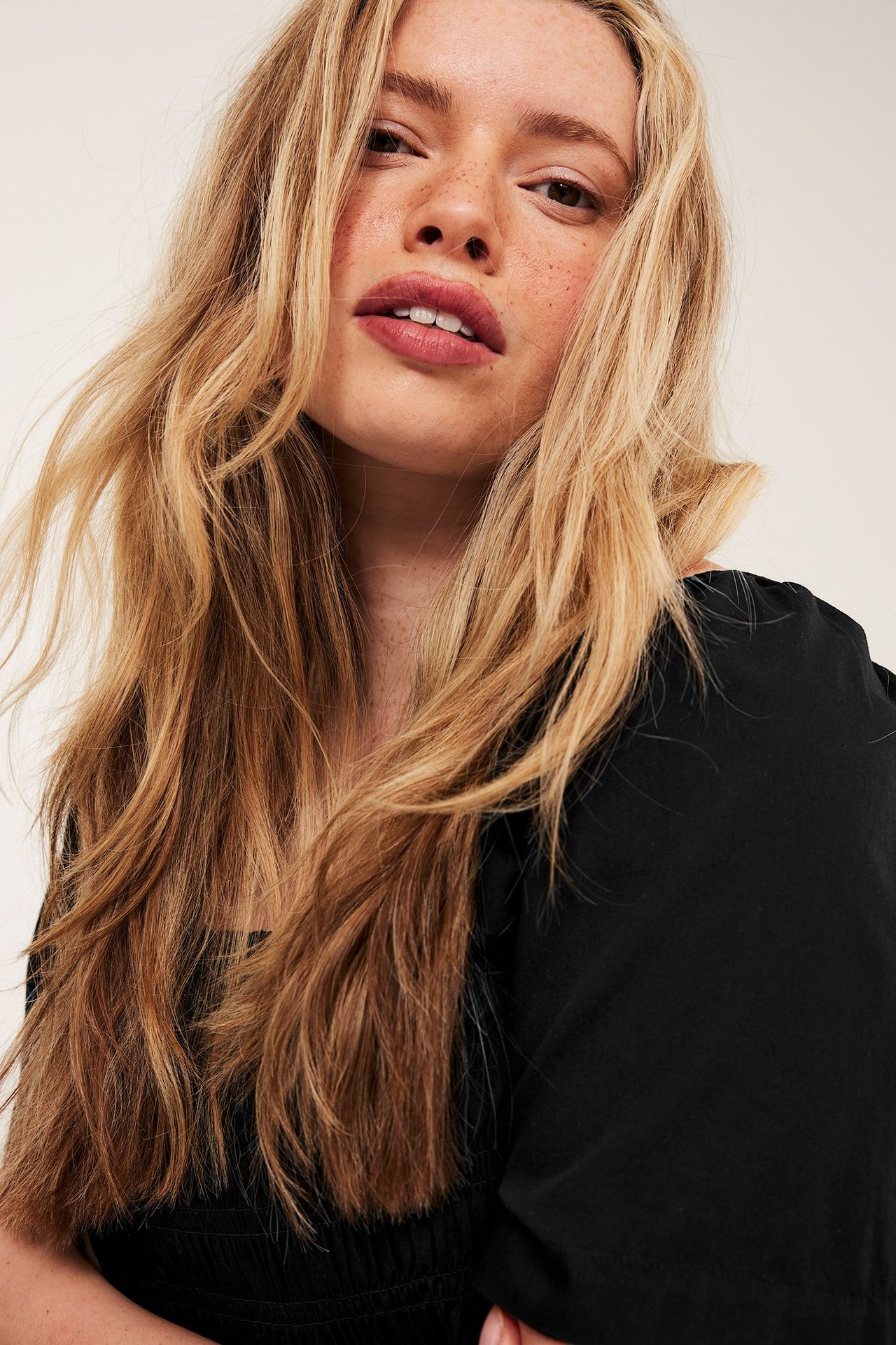 Närbild av en kvinna i en svart bomullspoplinklänning med smockdetaljer.