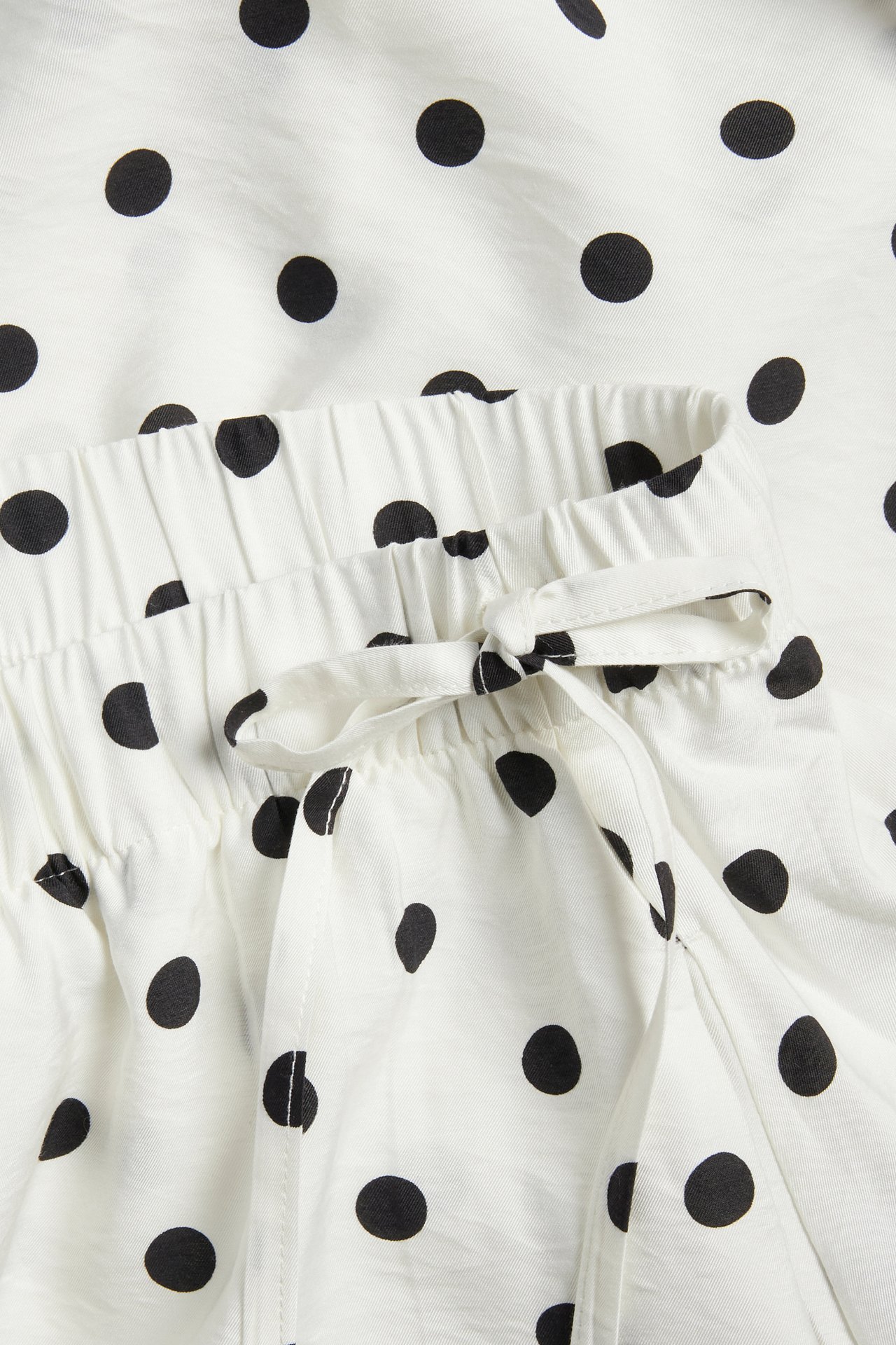 Lähikuva luonnonvalkoisesta pilkullisesta hameesta, jossa kuminauhavyötärö ja sidottu kiristysnyöri.