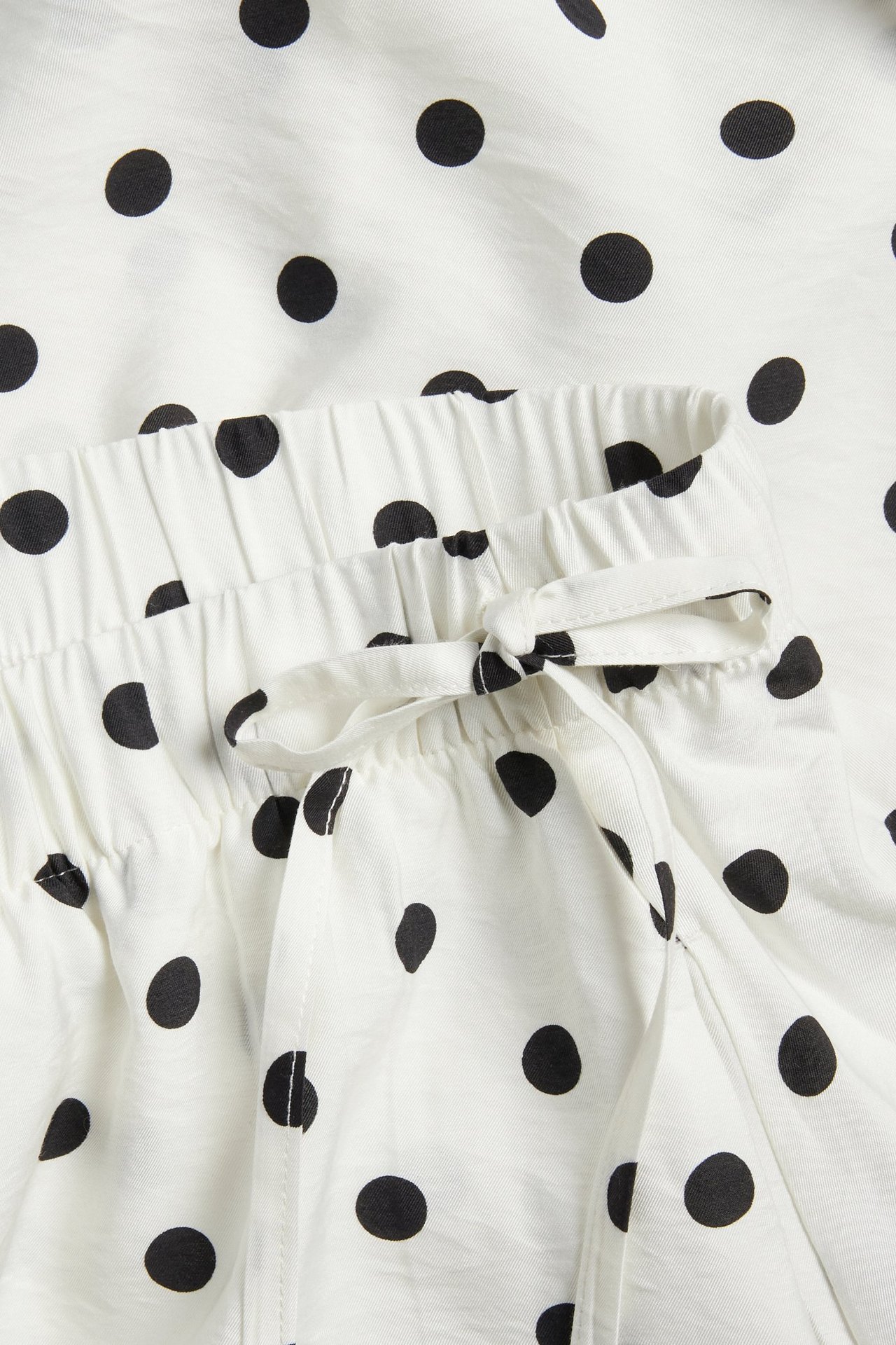 Lähikuva luonnonvalkoisesta pilkullisesta hameesta, jossa kuminauhavyötärö ja sidottu kiristysnyöri.