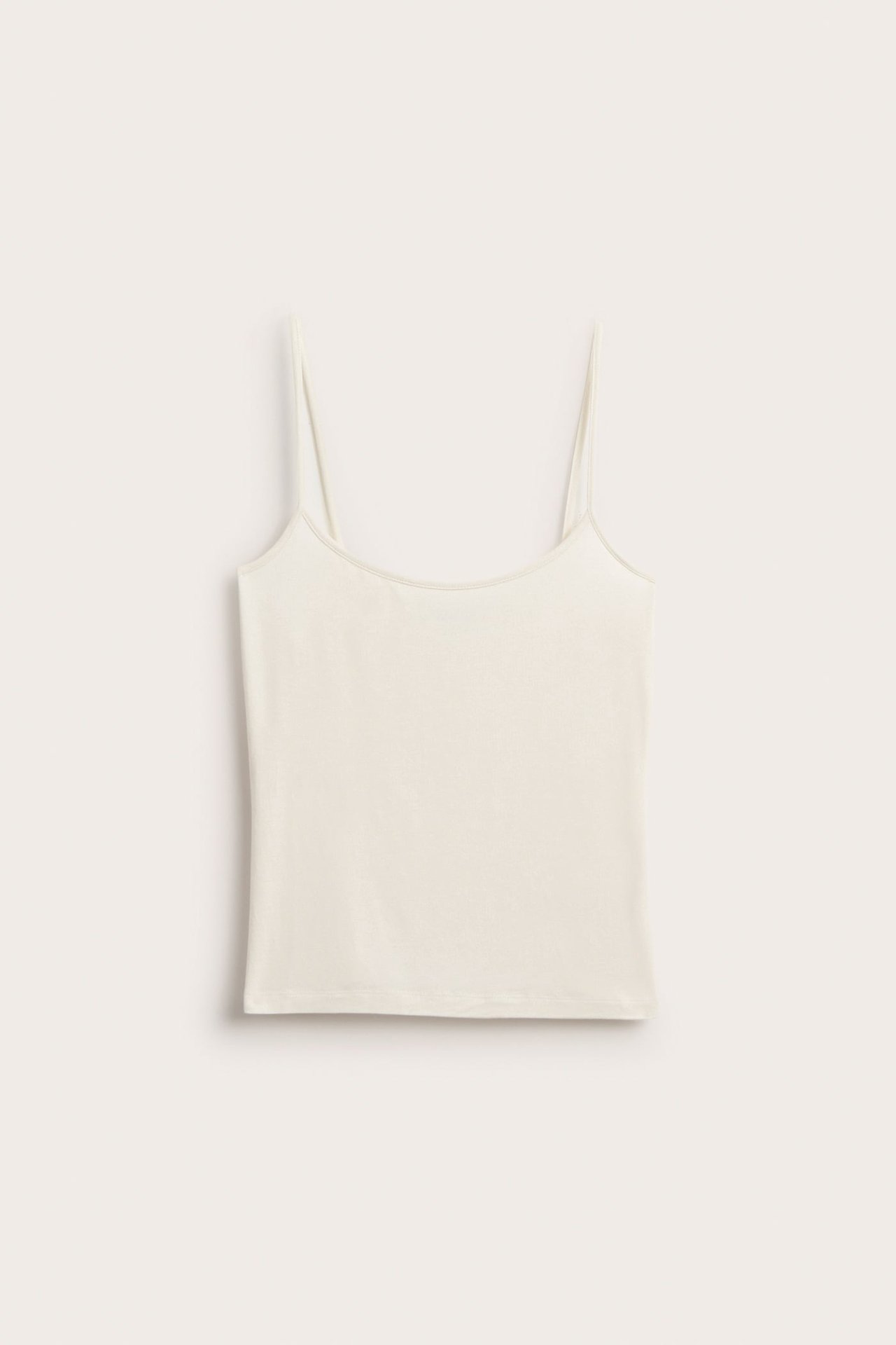 Frontbilde av en offwhite viskosesinglet med tynne stropper og rund hals, flatt lagt.